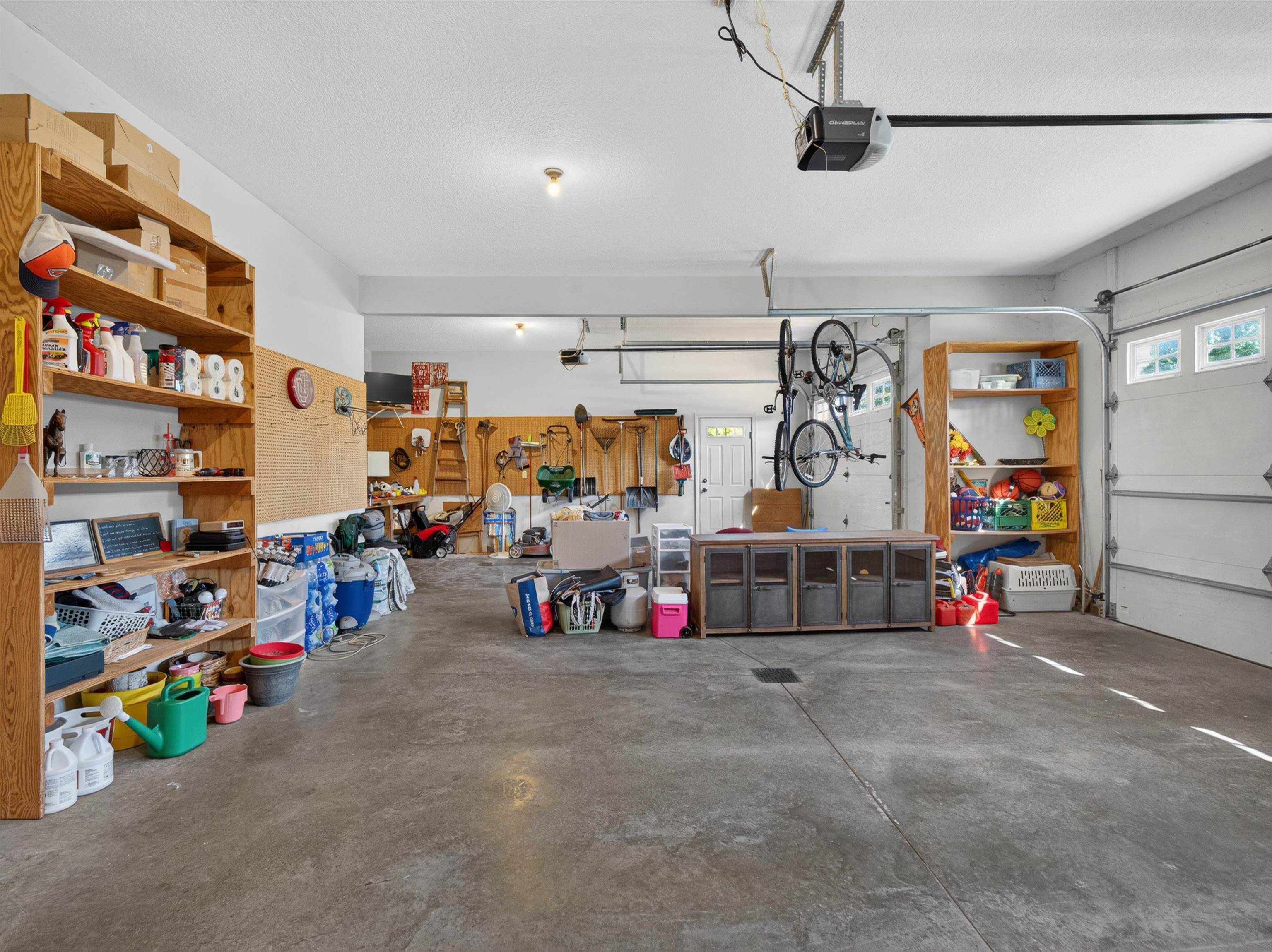 Spacious garage featuring a concrete floor, two overhead garage doors with window panels, and integrated ceiling lighting