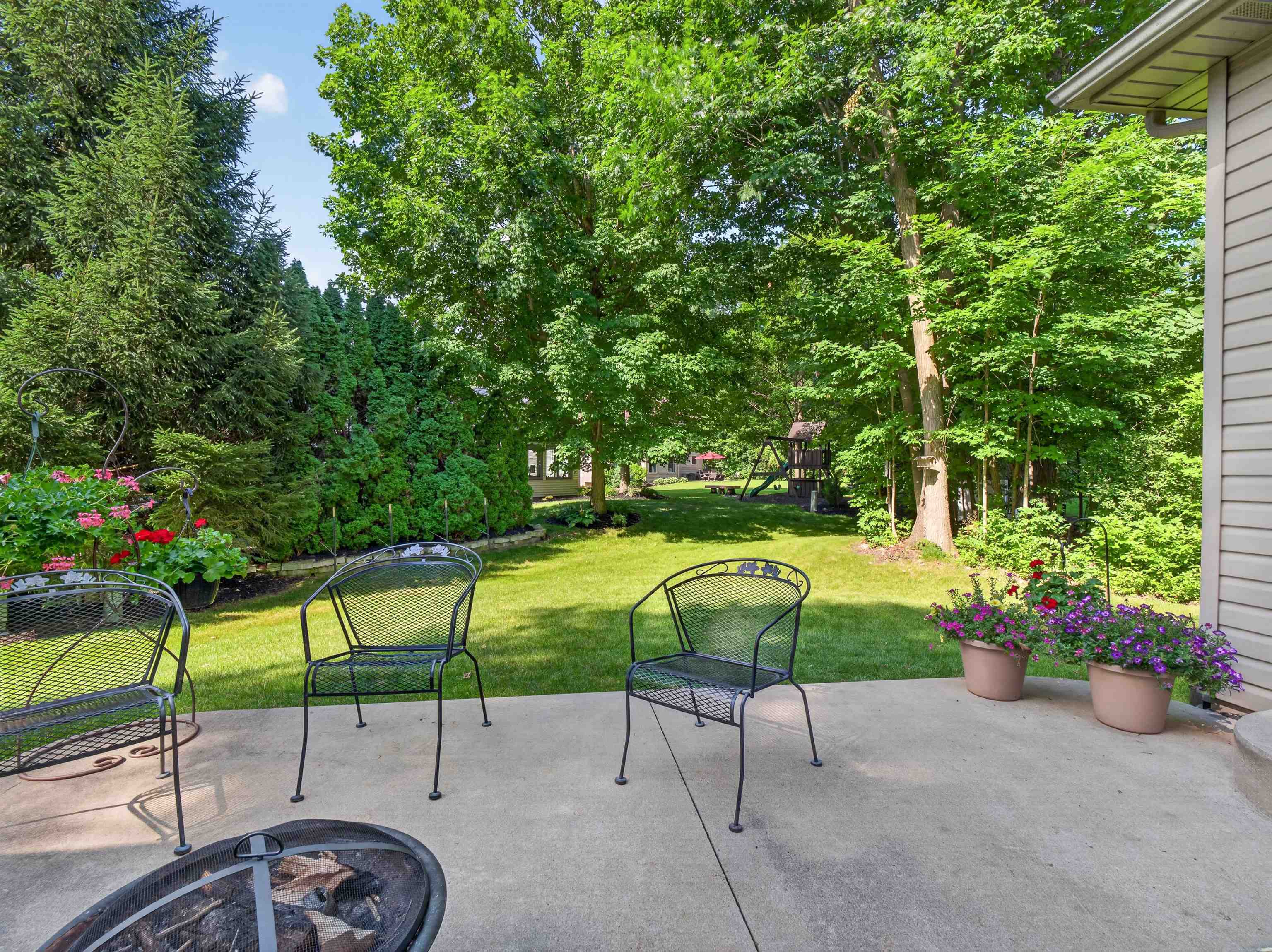Concrete patio featuring a fire pit and direct access to a spacious lawn