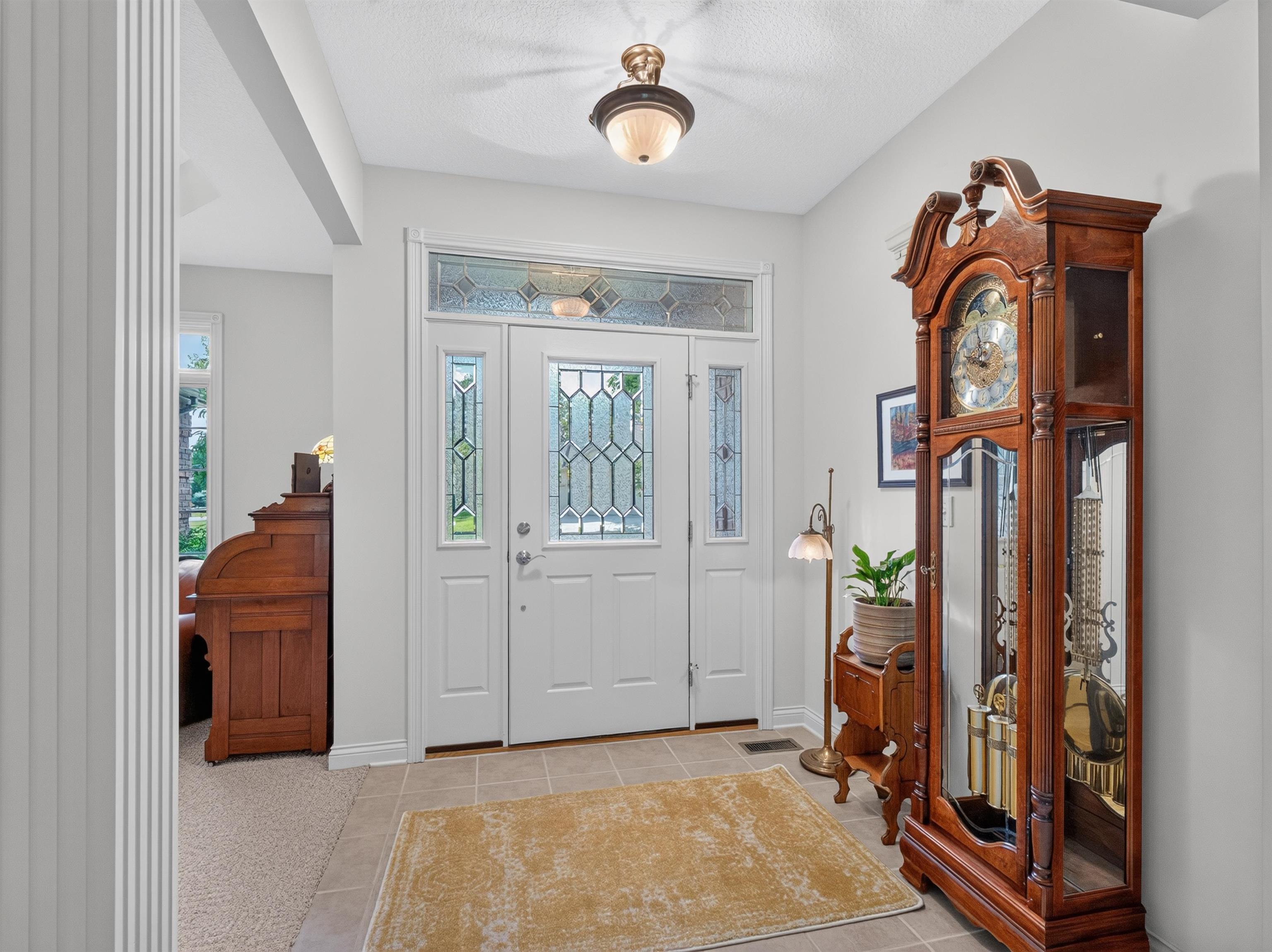 Entryway featuring a white paneled door with leaded glass inserts and an overhead transom window