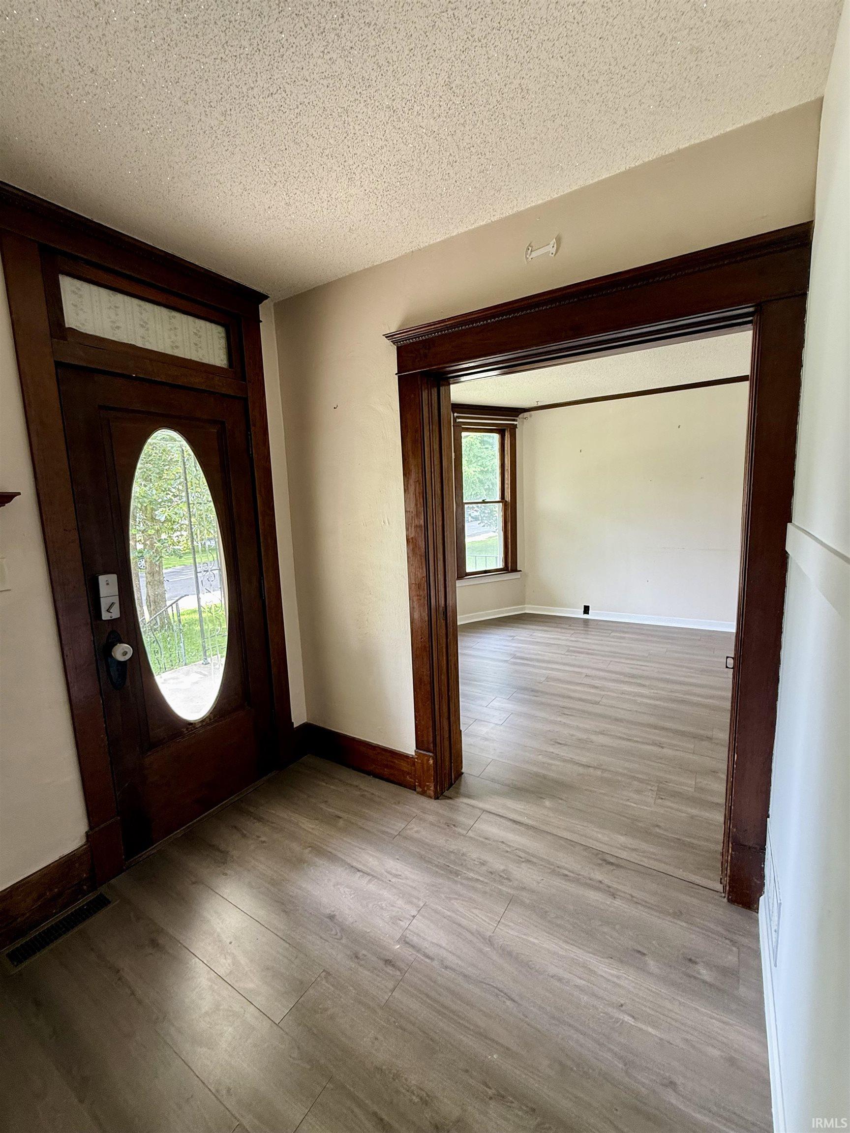 Entryway featuring a dark wood front door with an oval glass insert and transom window