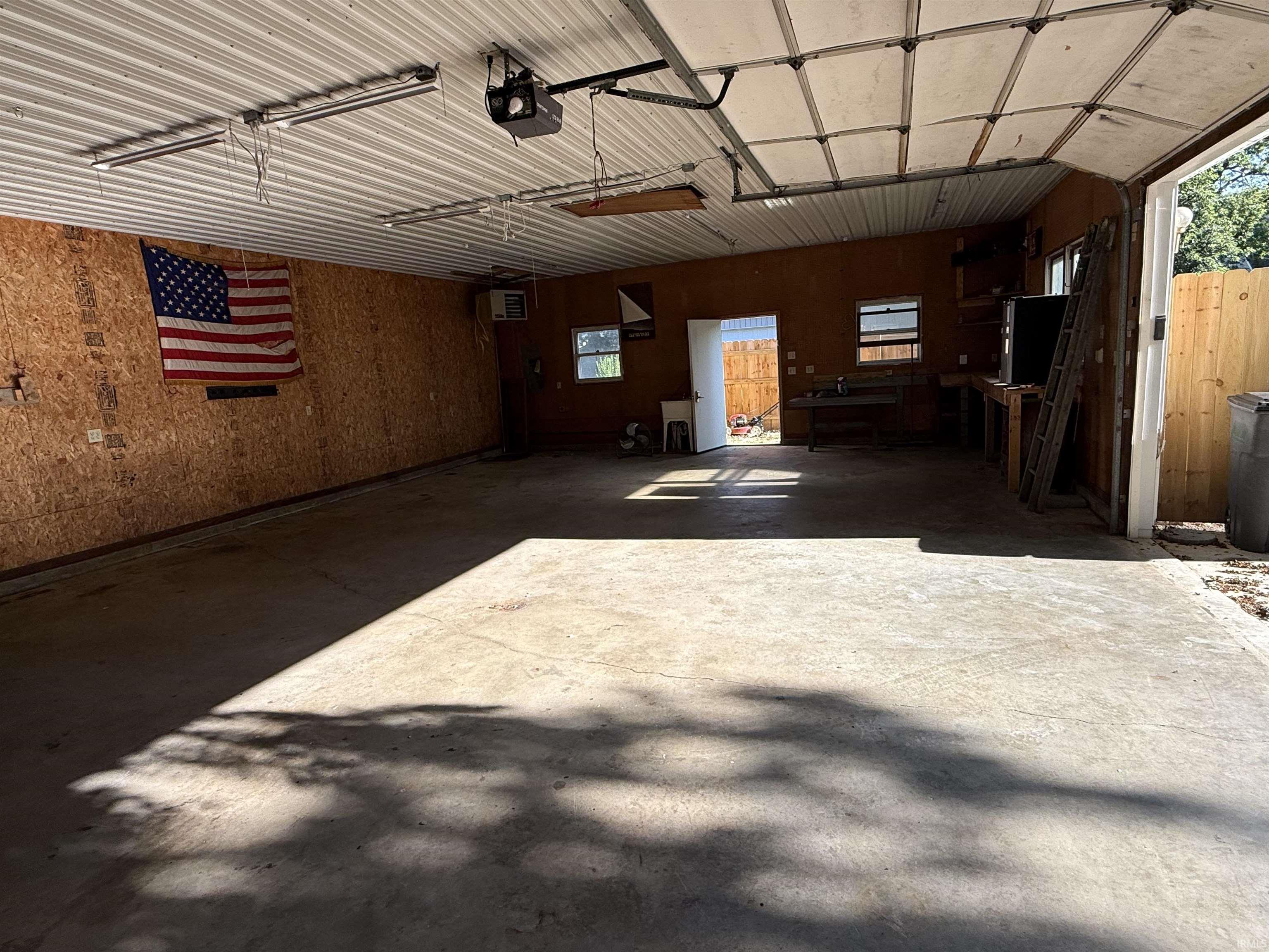 Spacious garage with concrete flooring, corrugated metal ceiling, and overhead lighting