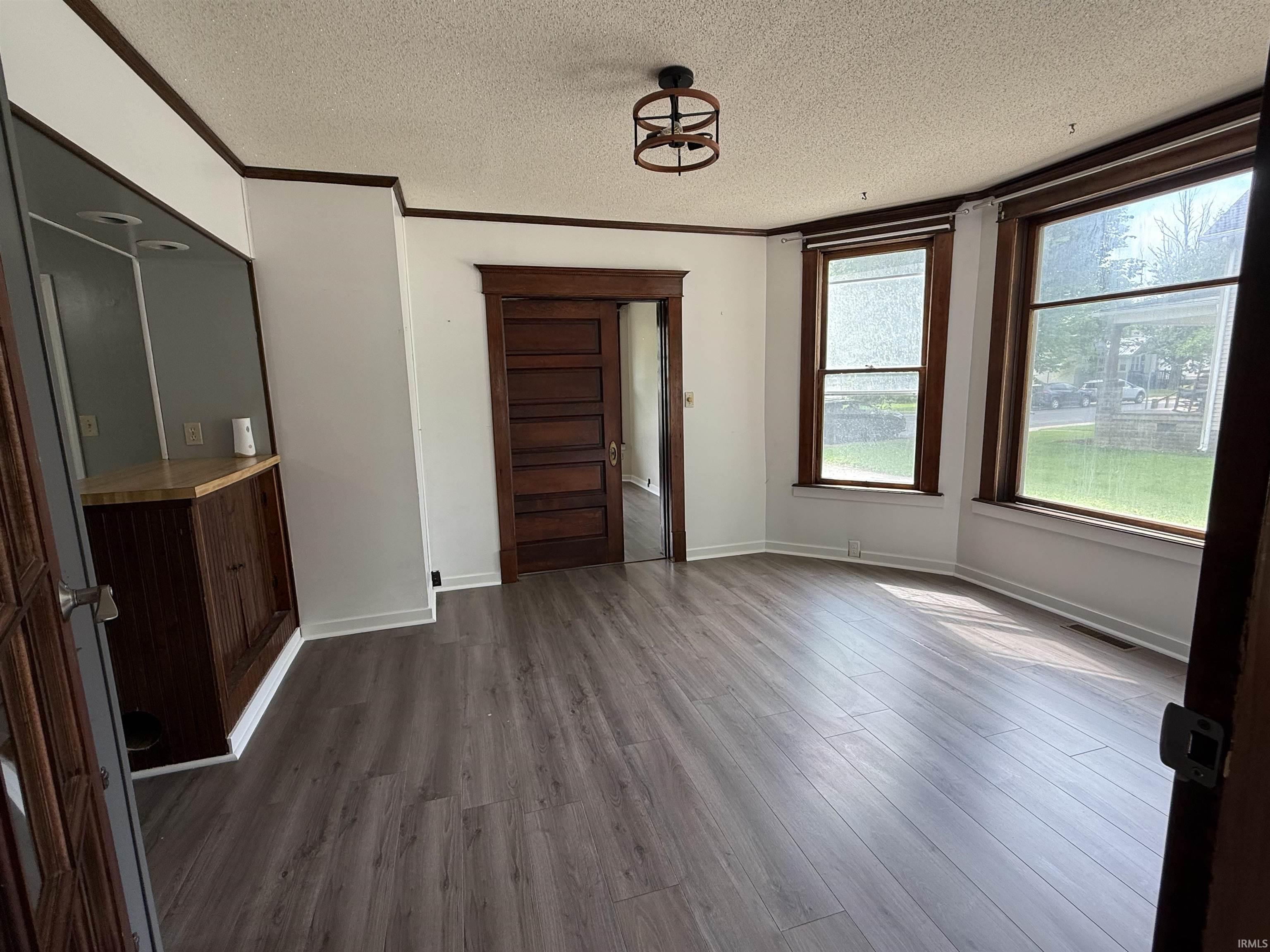 Spacious interior featuring wood-finish flooring, white walls, and dark wood trim