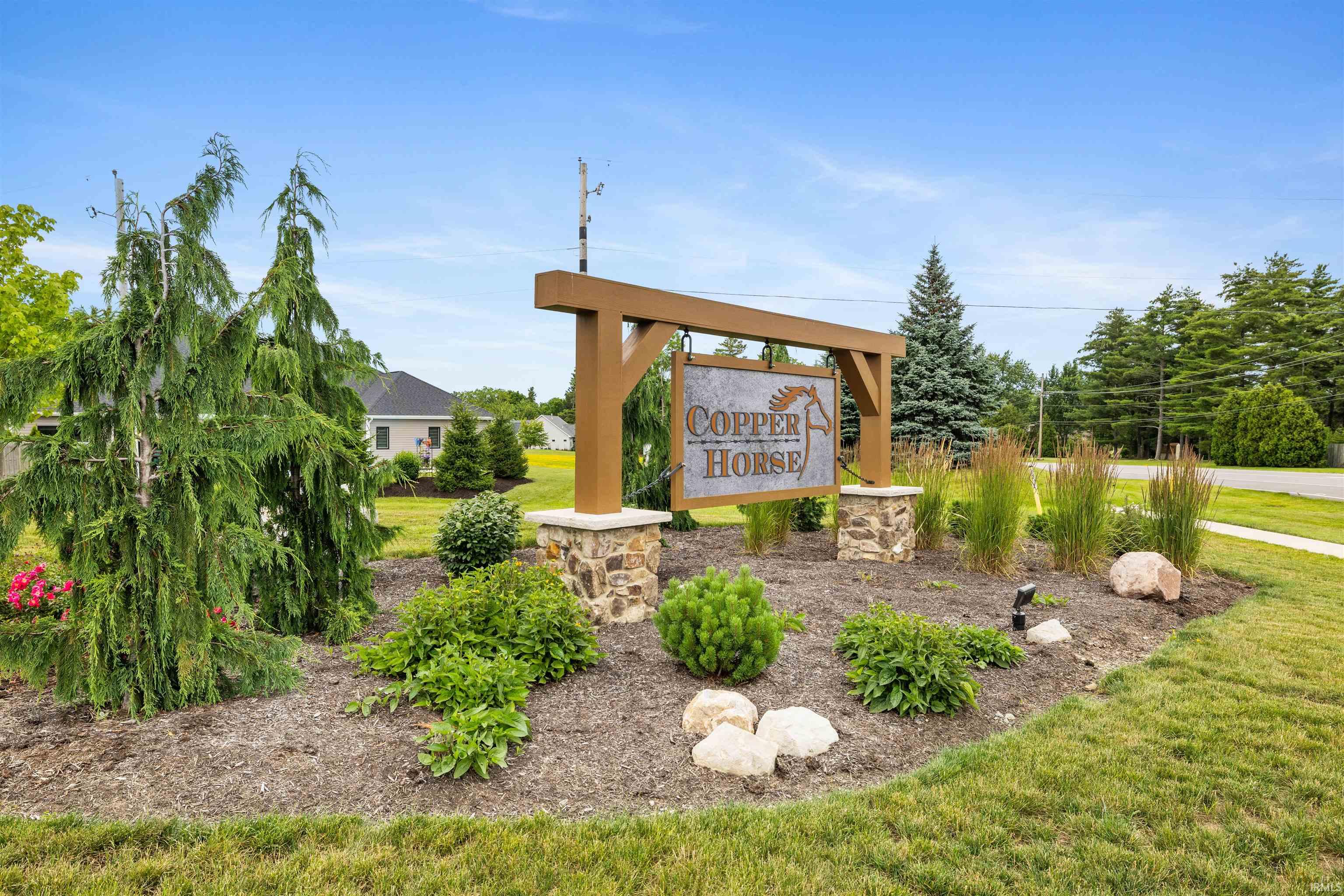 Entrance signage featuring a wood-finish frame, stone pillars, and a metal 