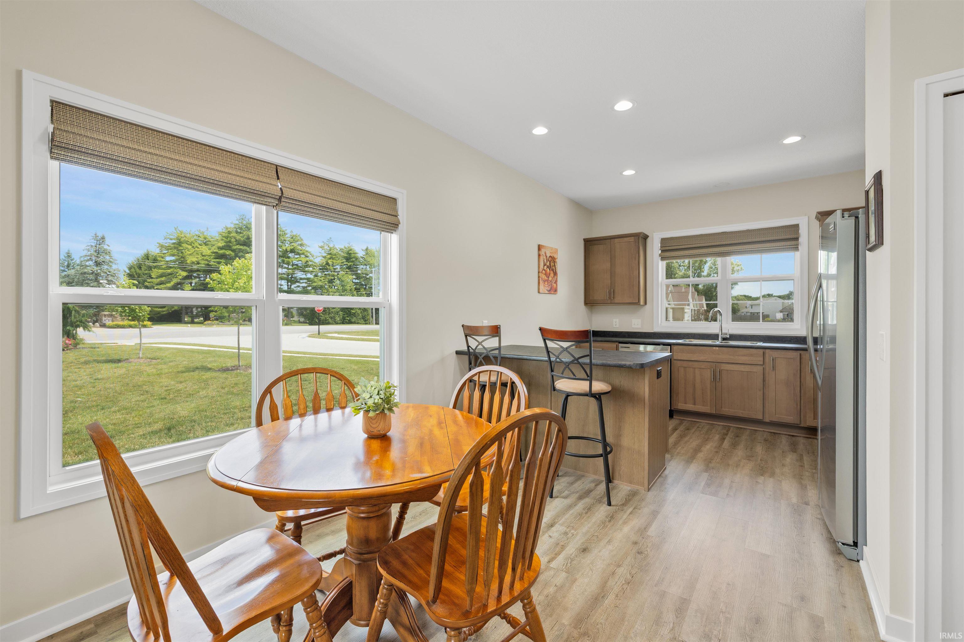 Kitchen featuring a peninsula with countertop seating, wood-finish flooring, recessed lighting, and a stainless steel refrigerator