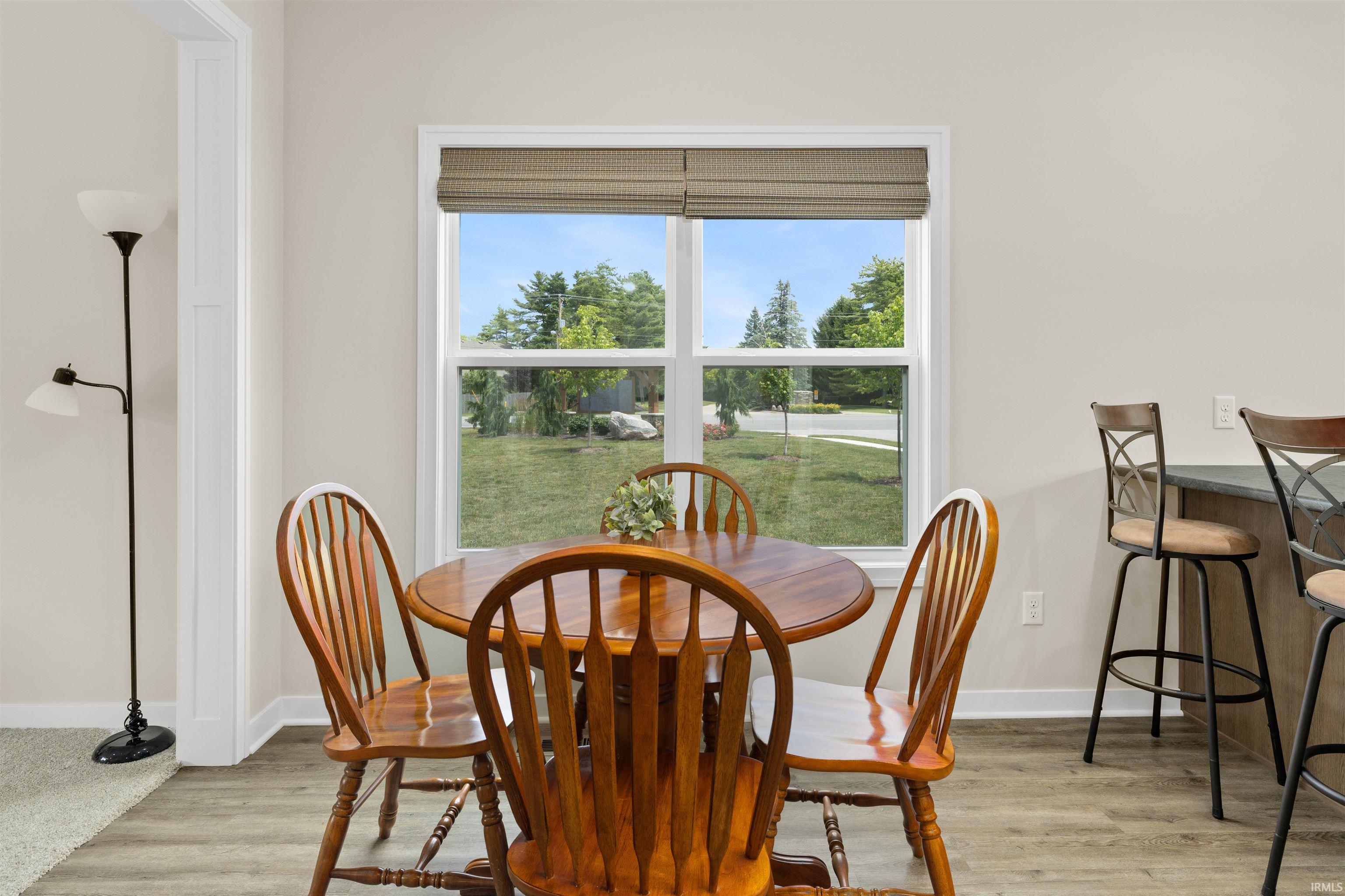 Dining area featuring a large window with horizontal blinds, wood-finish flooring, and a breakfast bar with a dark countertop