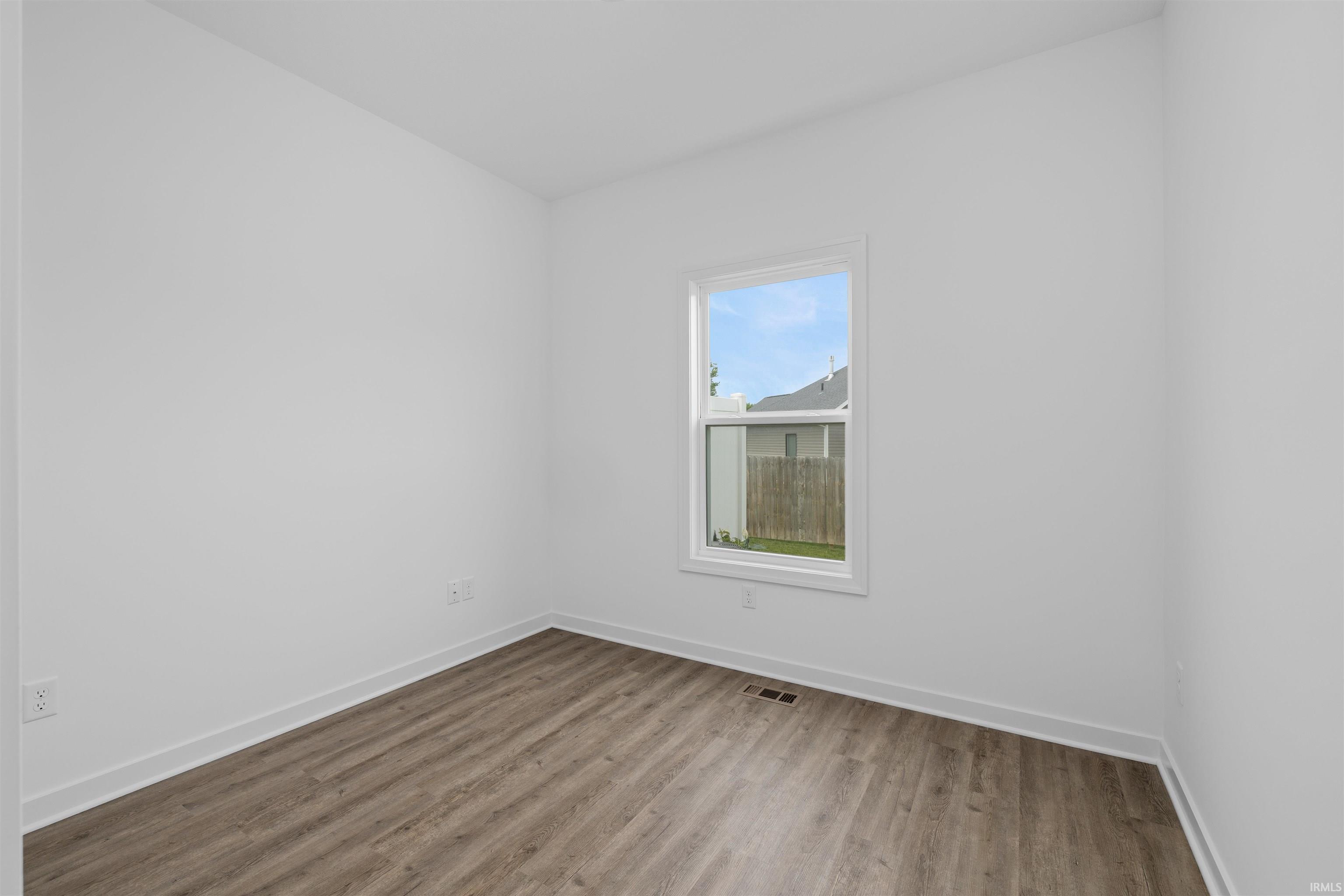 Room featuring light wood-finish flooring, white walls, white trim, and a white-framed window