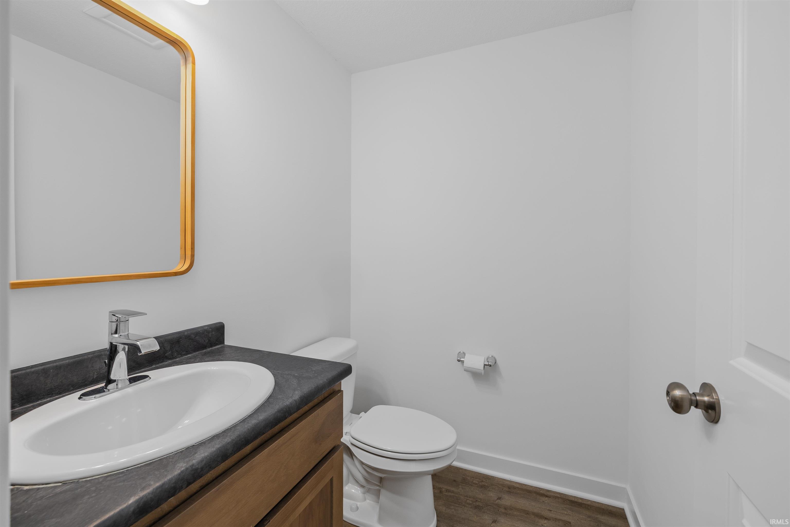 Bathroom featuring a vanity with a white oval sink, dark countertop, and wood-finish cabinetry