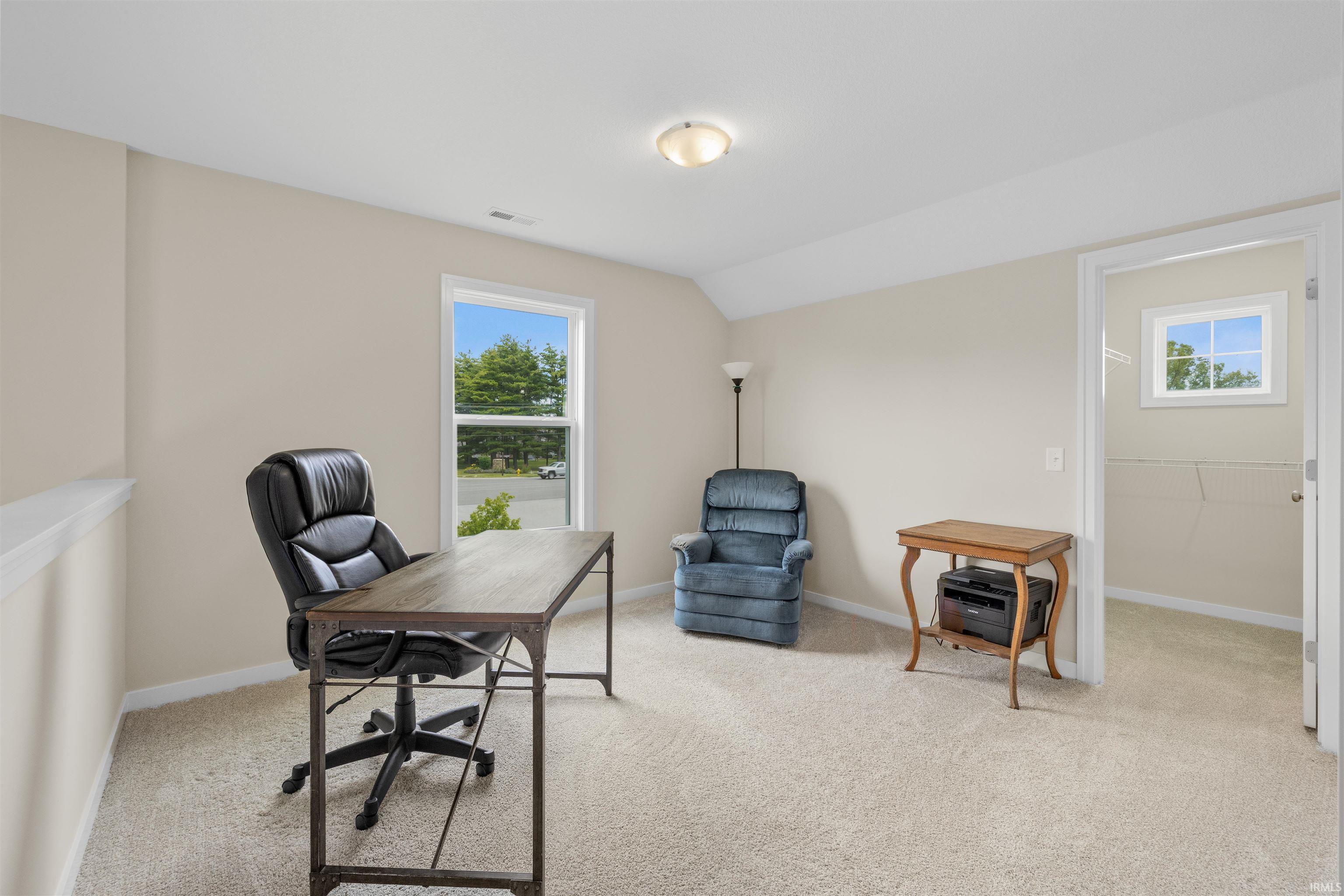 Carpeted room with a vaulted ceiling, recessed lighting, and a window offering natural light
