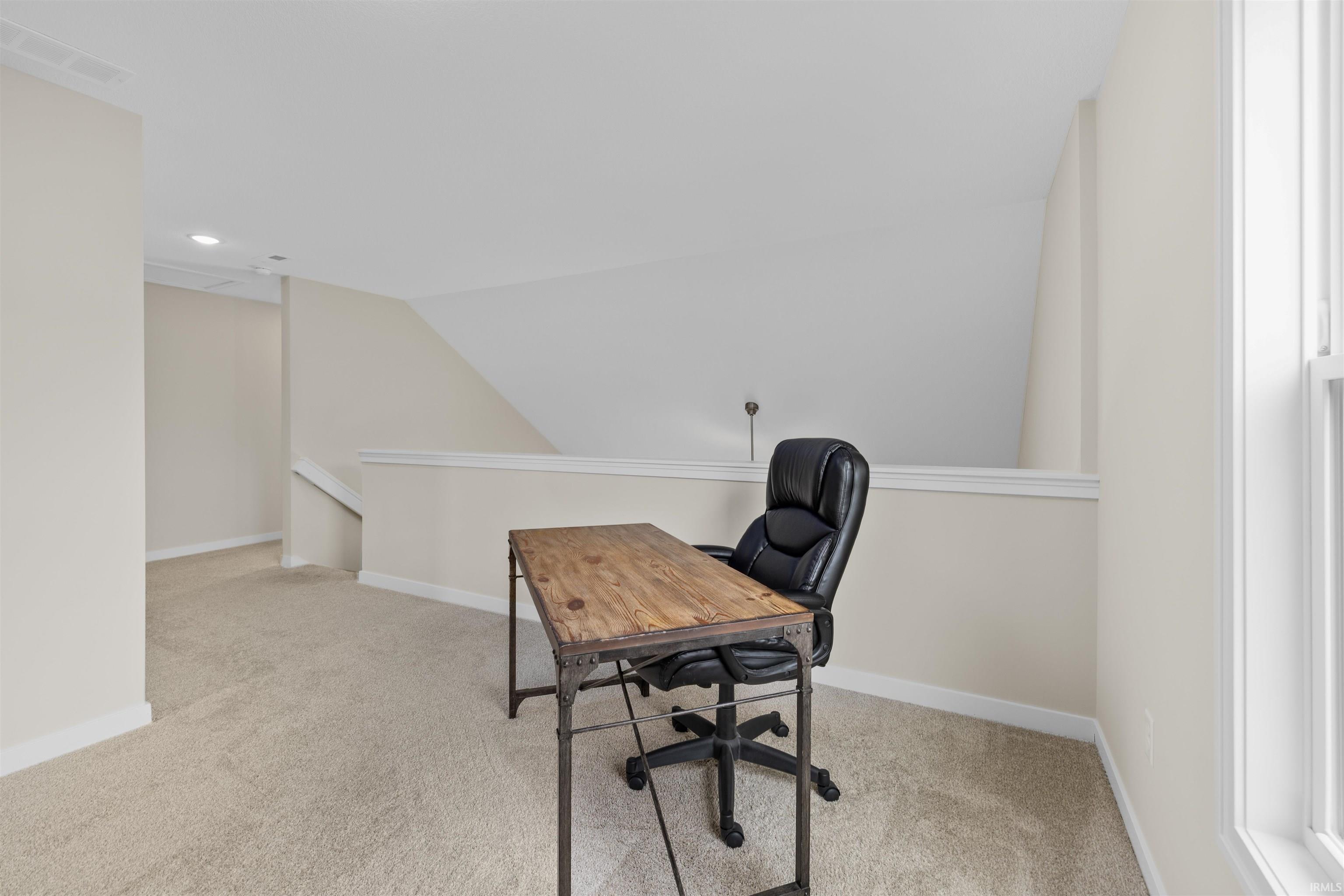 Carpeted loft area featuring a window, painted walls, and a partial wall with white trim
