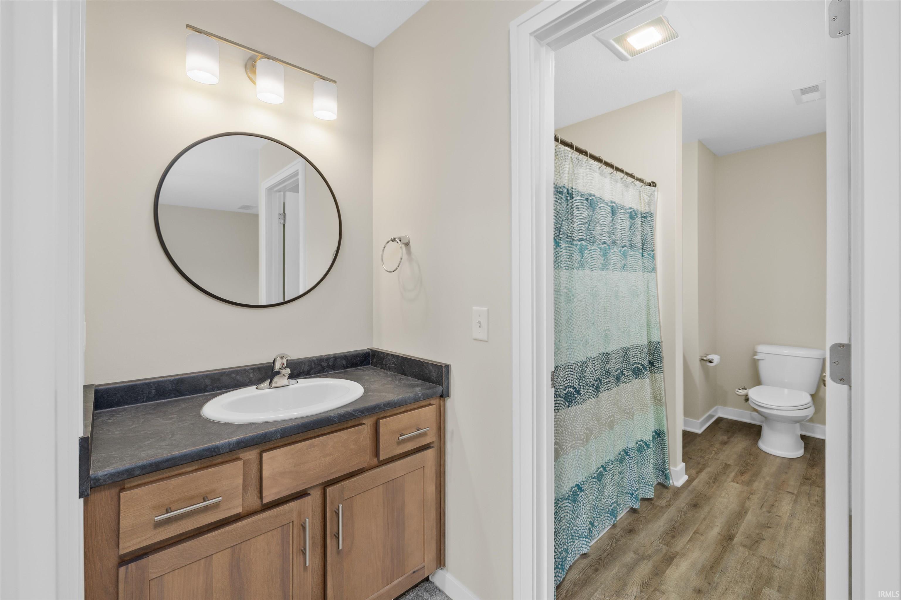 Bathroom vanity with a dark countertop and wood-finish cabinetry