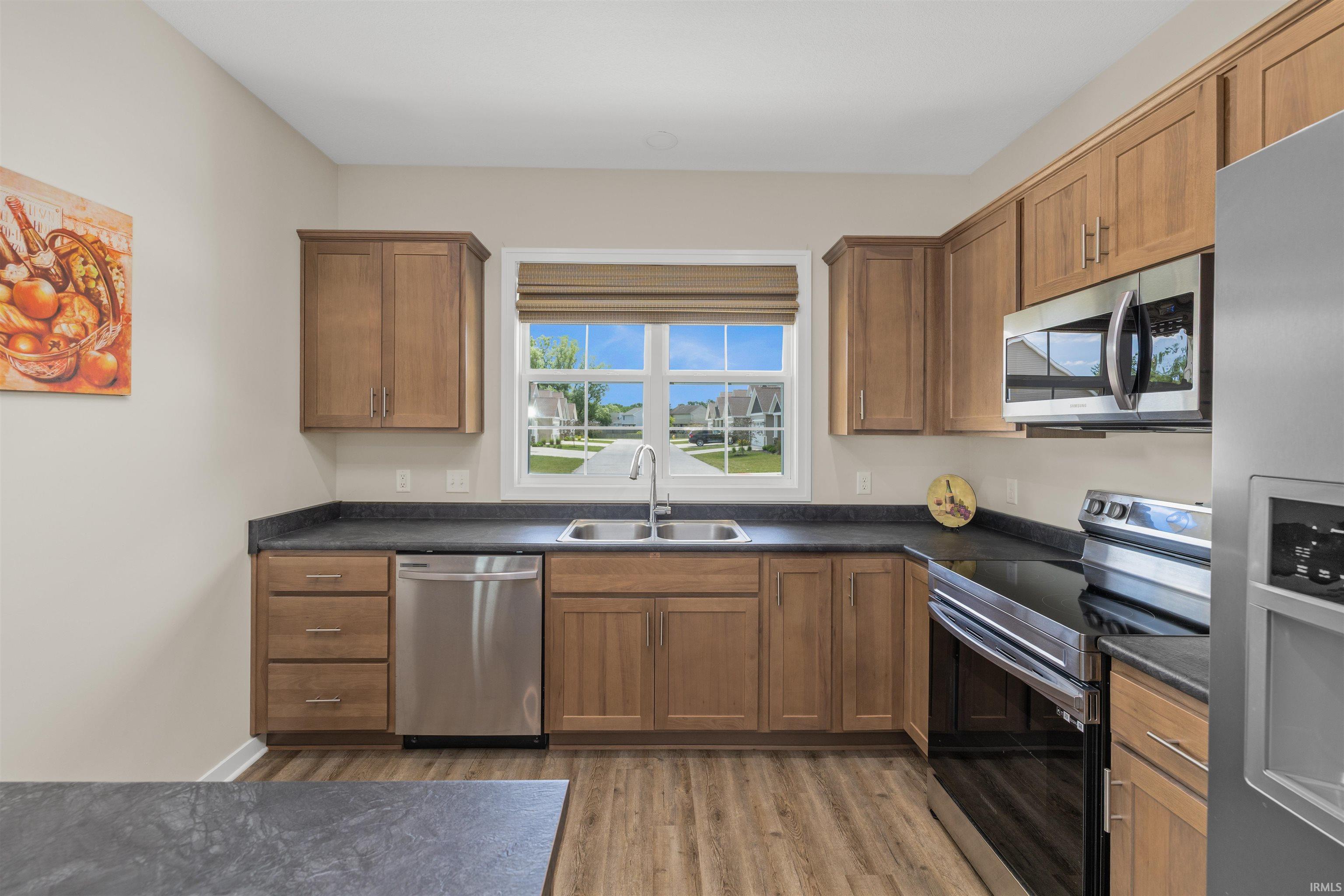 Kitchen featuring wood-finish cabinetry, dark countertops, a stainless steel sink, and stainless steel appliances
