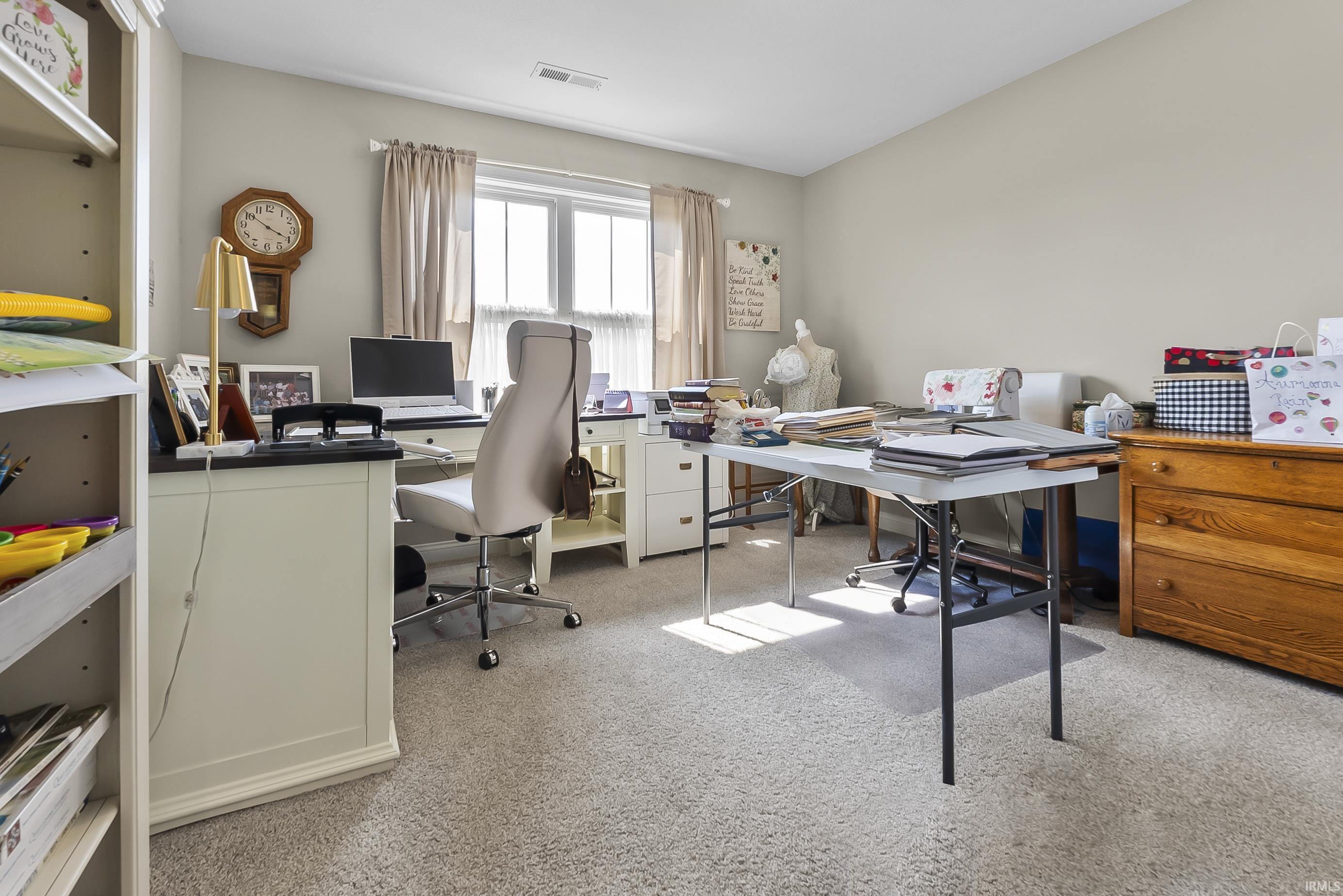 Carpeted room with a double window, light neutral wall color, and a built-in shelving unit