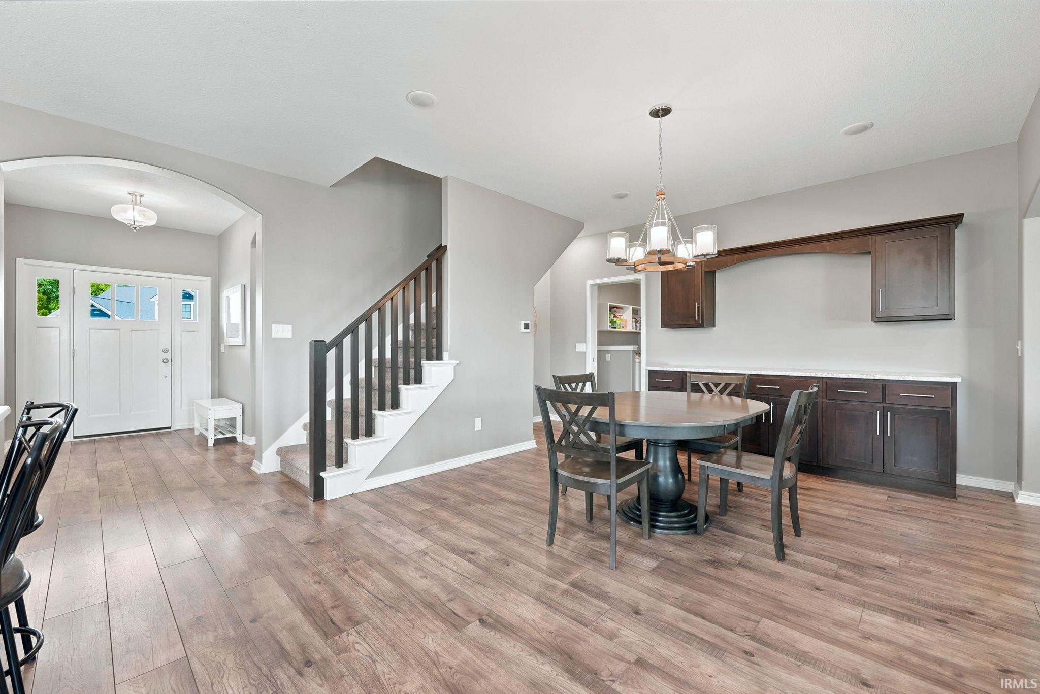 Open living area featuring wood-finish flooring and a central staircase with dark wood newel posts and spindles