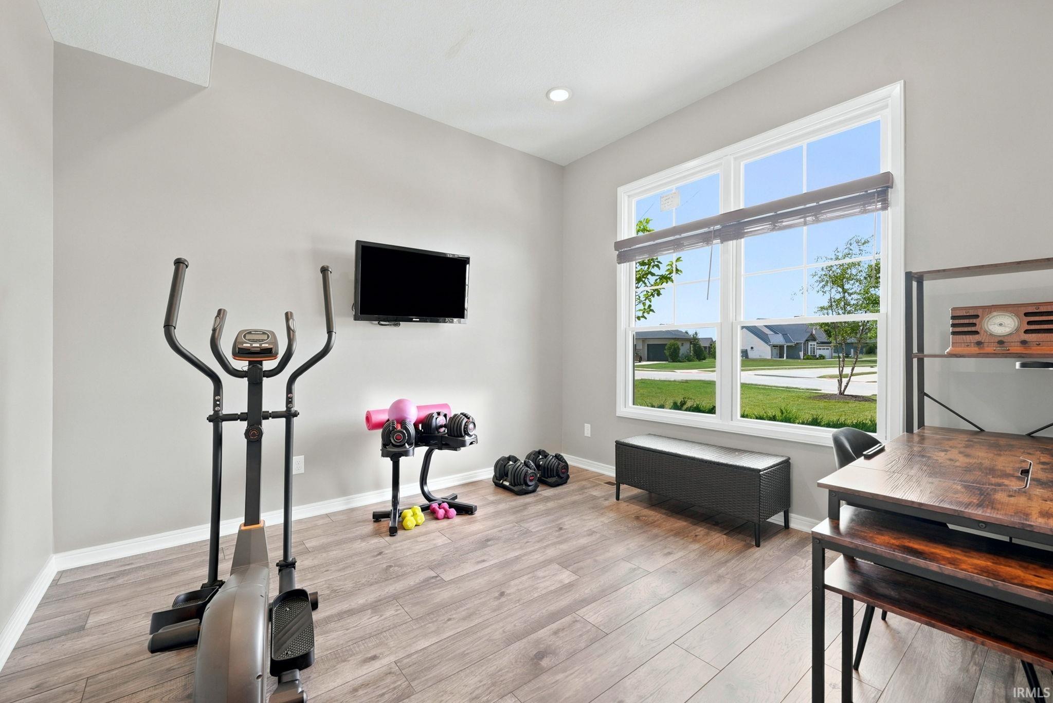 Versatile room featuring large windows, wood-finish flooring, recessed lighting, and neutral wall tones