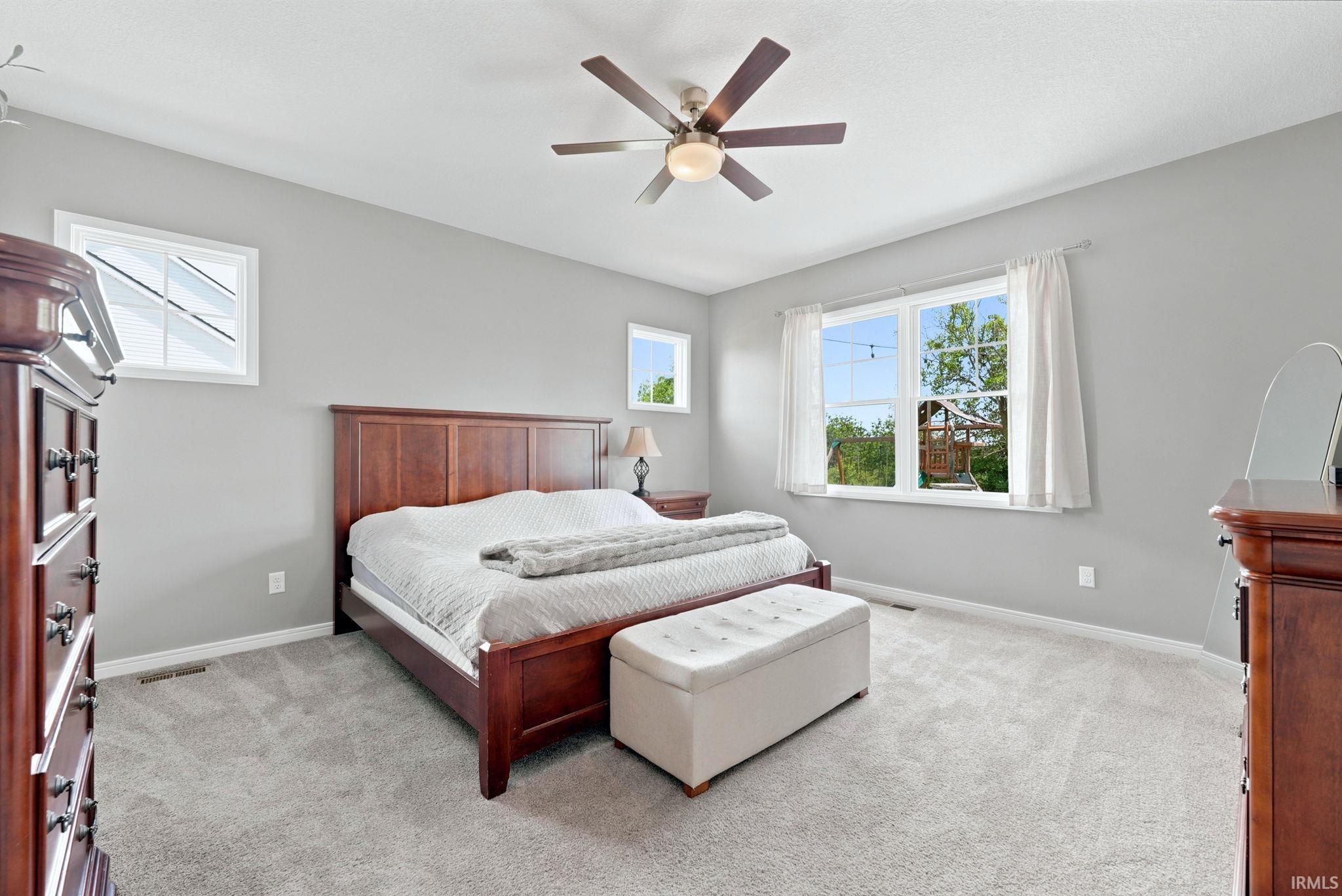 Spacious room with light gray walls, plush gray carpeting, and multiple windows
