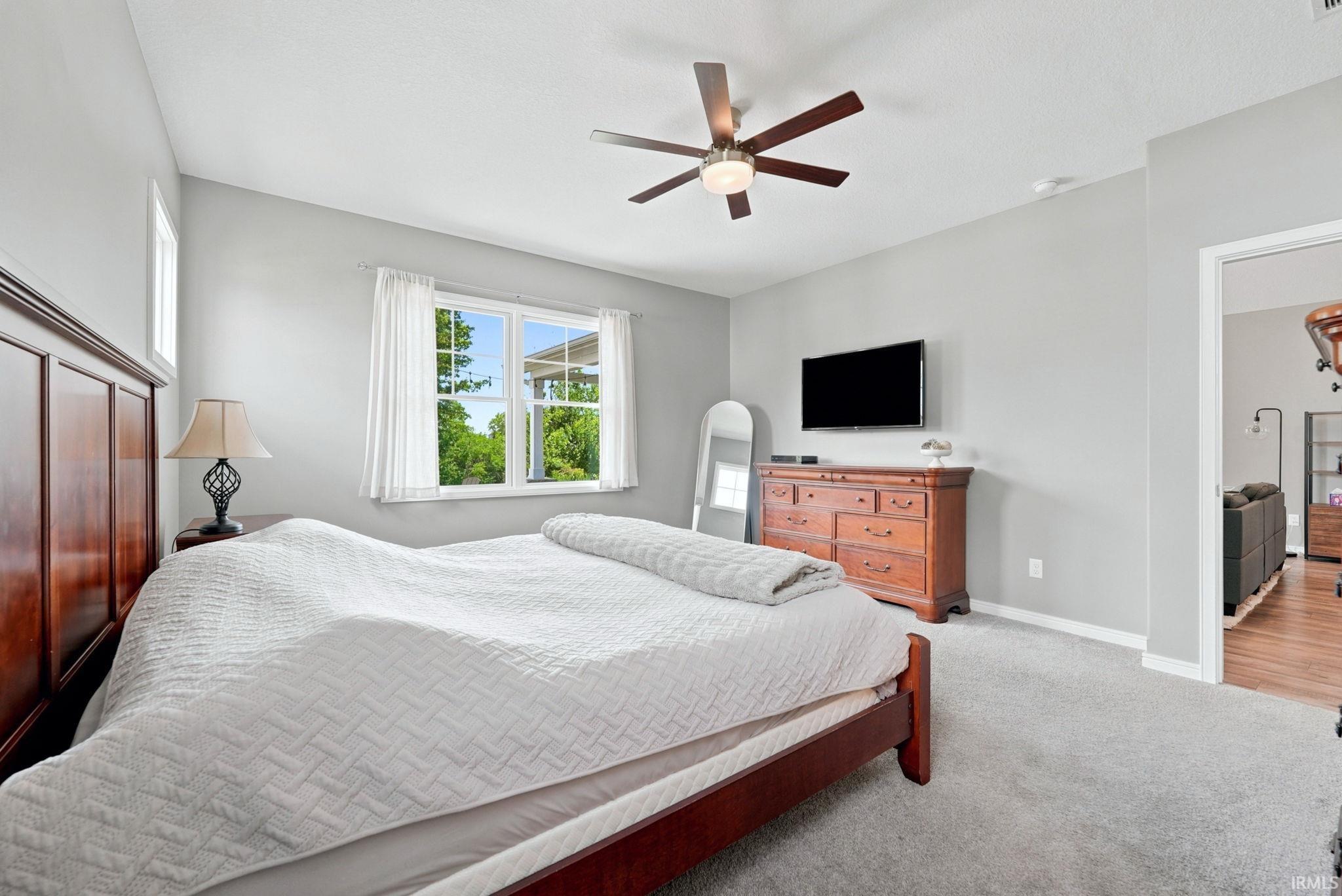 Bedroom featuring neutral wall paint, light gray carpeting, and a ceiling fan with integrated lighting