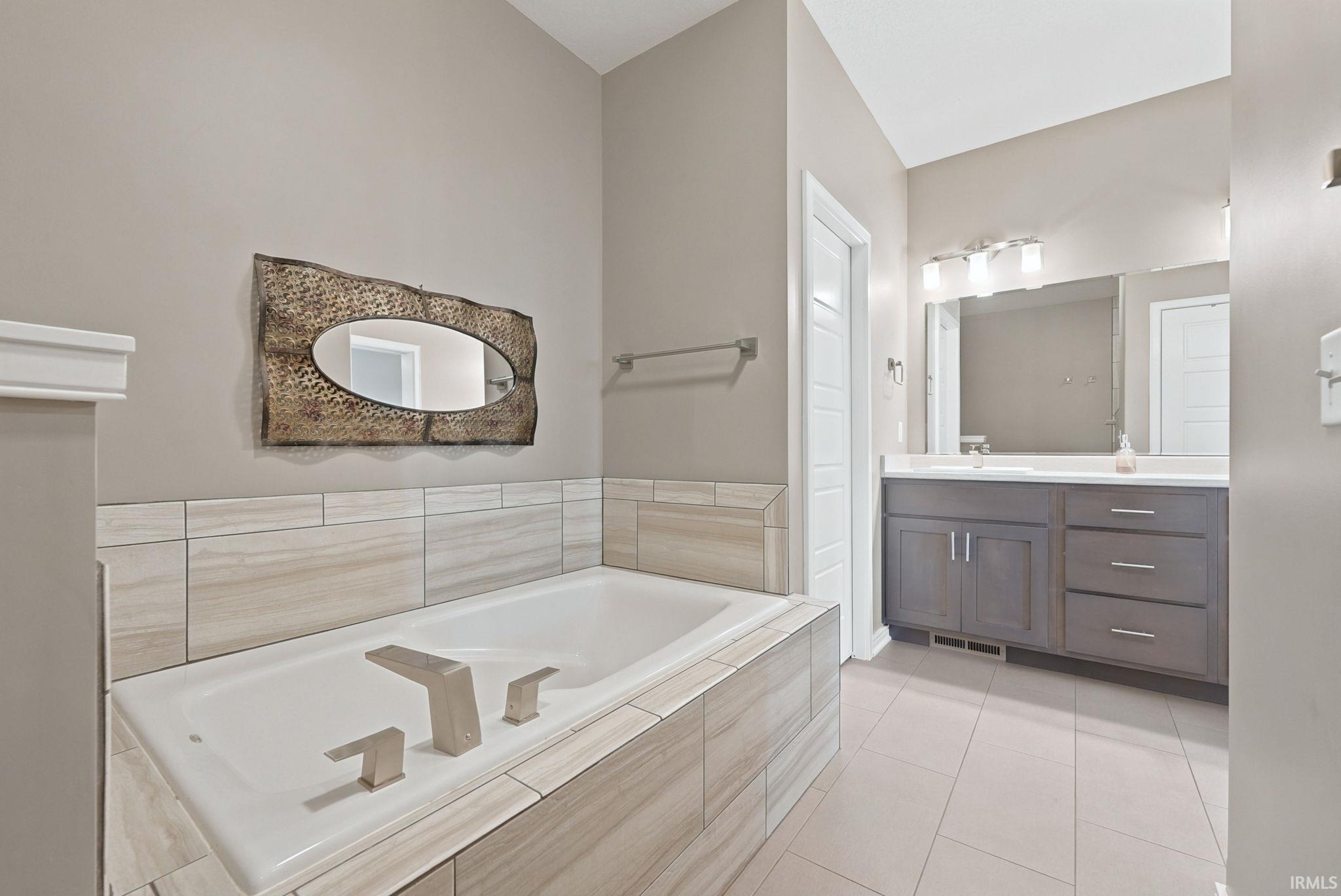 Soaking tub with brushed nickel fixtures, surrounded by large format tile