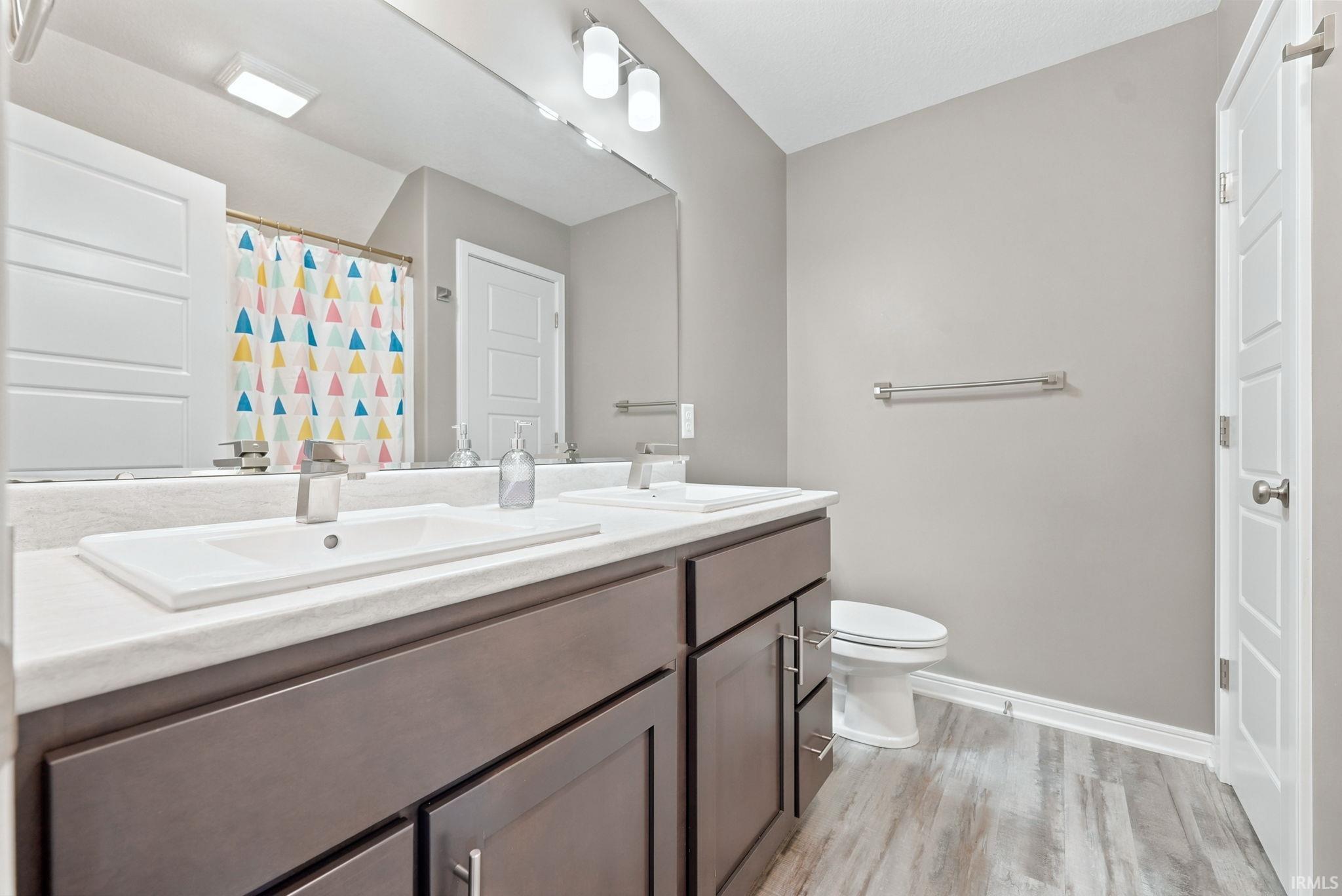 Dual vanity with white undermount sinks, contemporary chrome faucets, and dark wood-finish cabinetry