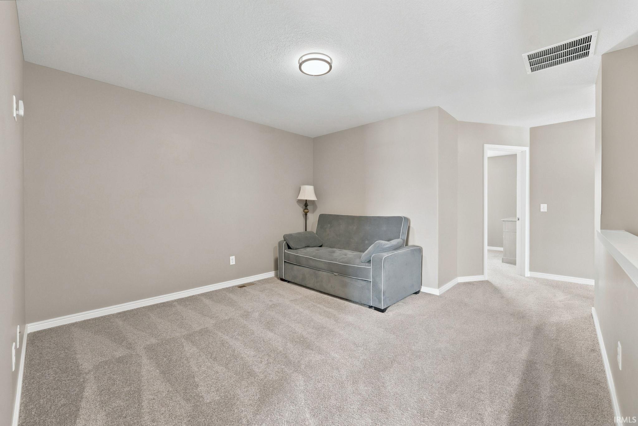 Carpeted room with neutral paint, white baseboards, a flush-mount ceiling light, and a visible doorway