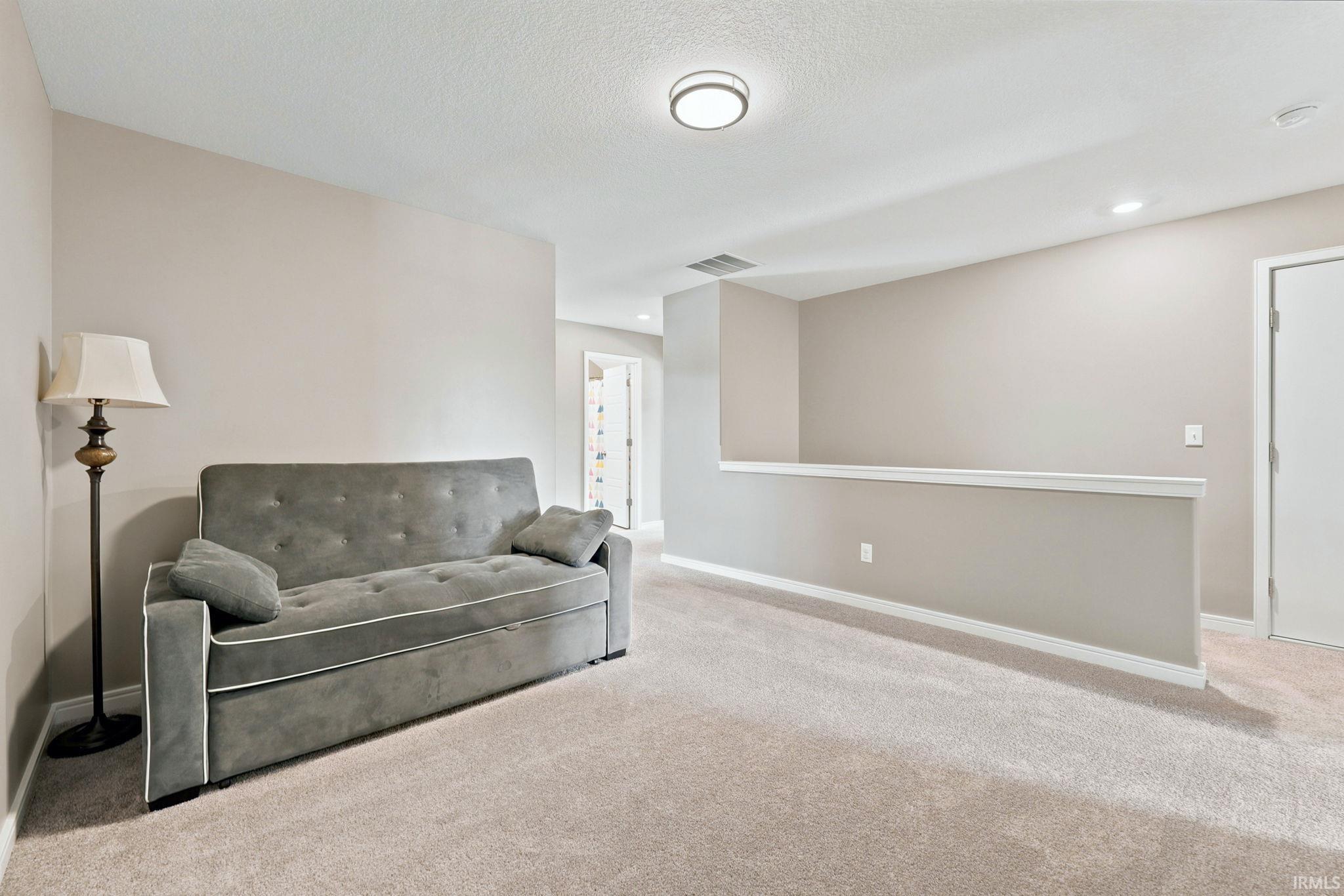Carpeted loft space featuring neutral wall tones, recessed lighting, and a white interior door