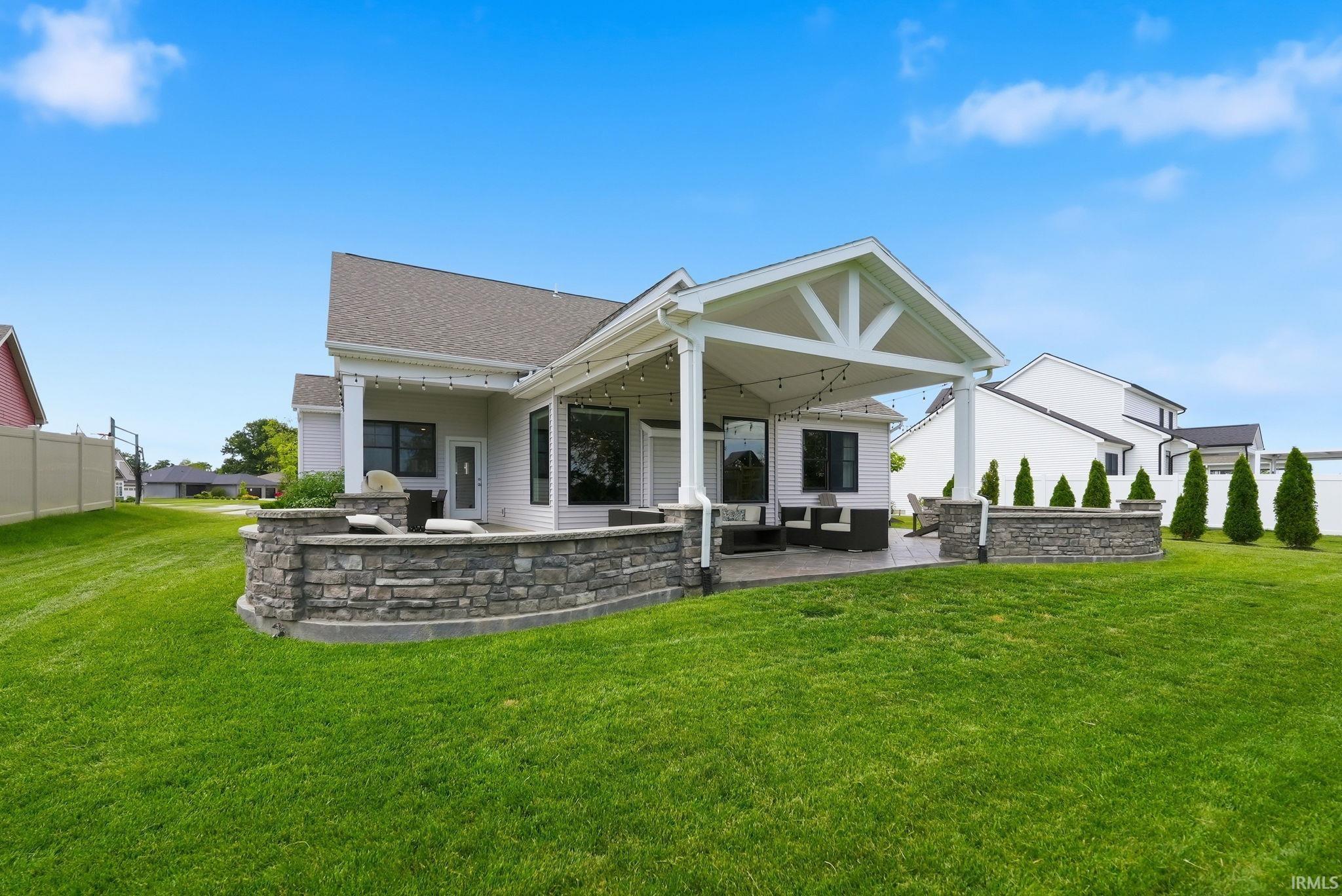 Expansive backyard featuring a covered patio with exposed beam truss details