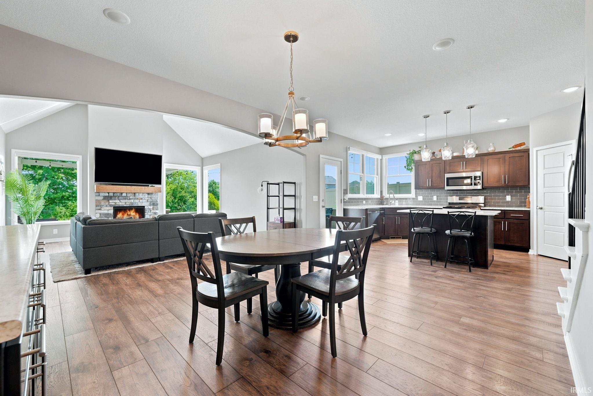 Open-concept living area featuring a vaulted ceiling and wood-finish flooring