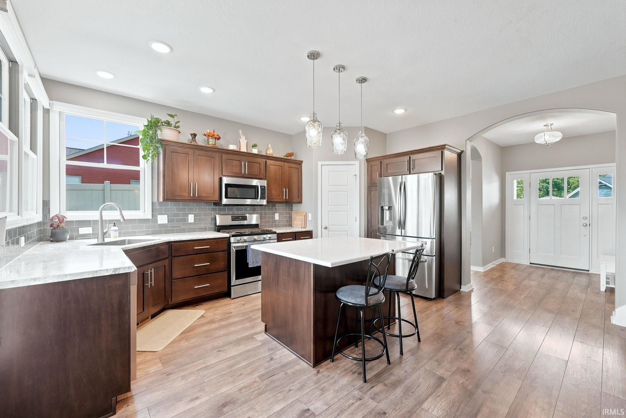 Modern kitchen featuring wood-finish flooring, recessed lighting, and a kitchen island with pendant lights