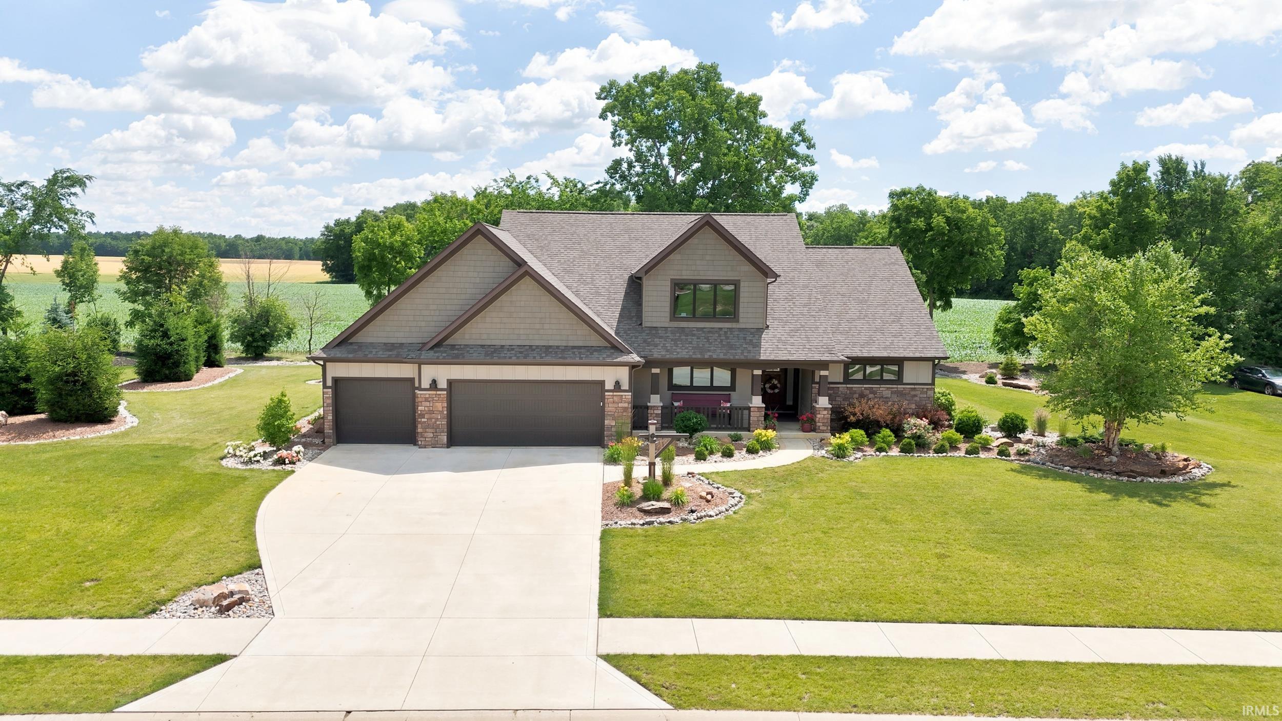 Contemporary Craftsman-style residence featuring a prominent stone and siding exterior, an attached two-car garage, and a concrete driveway