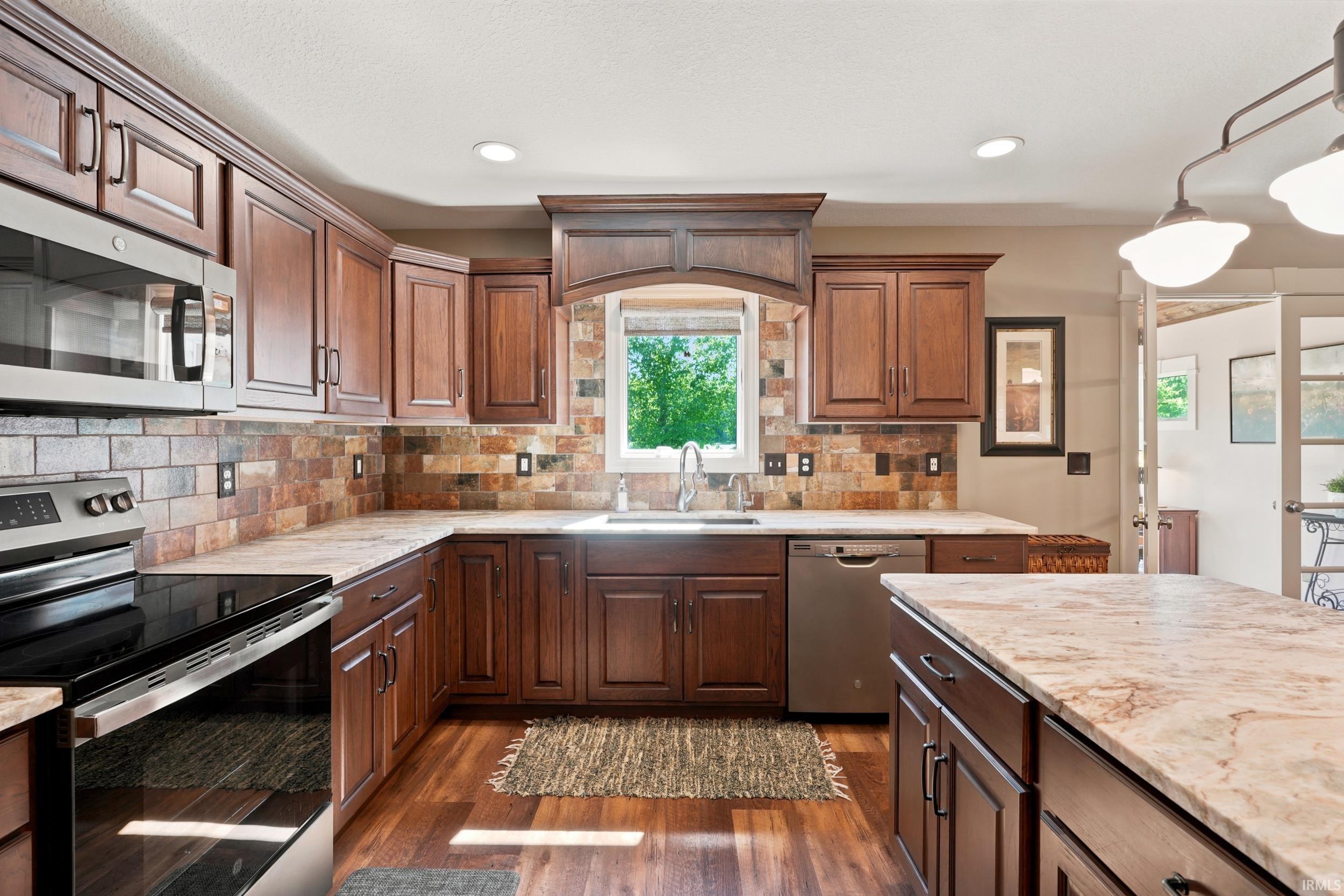 Kitchen featuring wood-finish flooring, dark wood cabinetry, a tiled backsplash, and stainless steel appliances