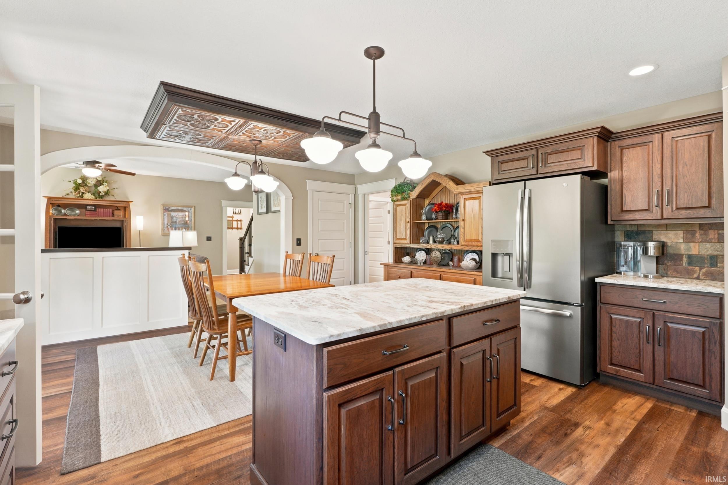 Kitchen featuring a central island with a light-toned countertop, wood-finish flooring, and dark wood cabinetry