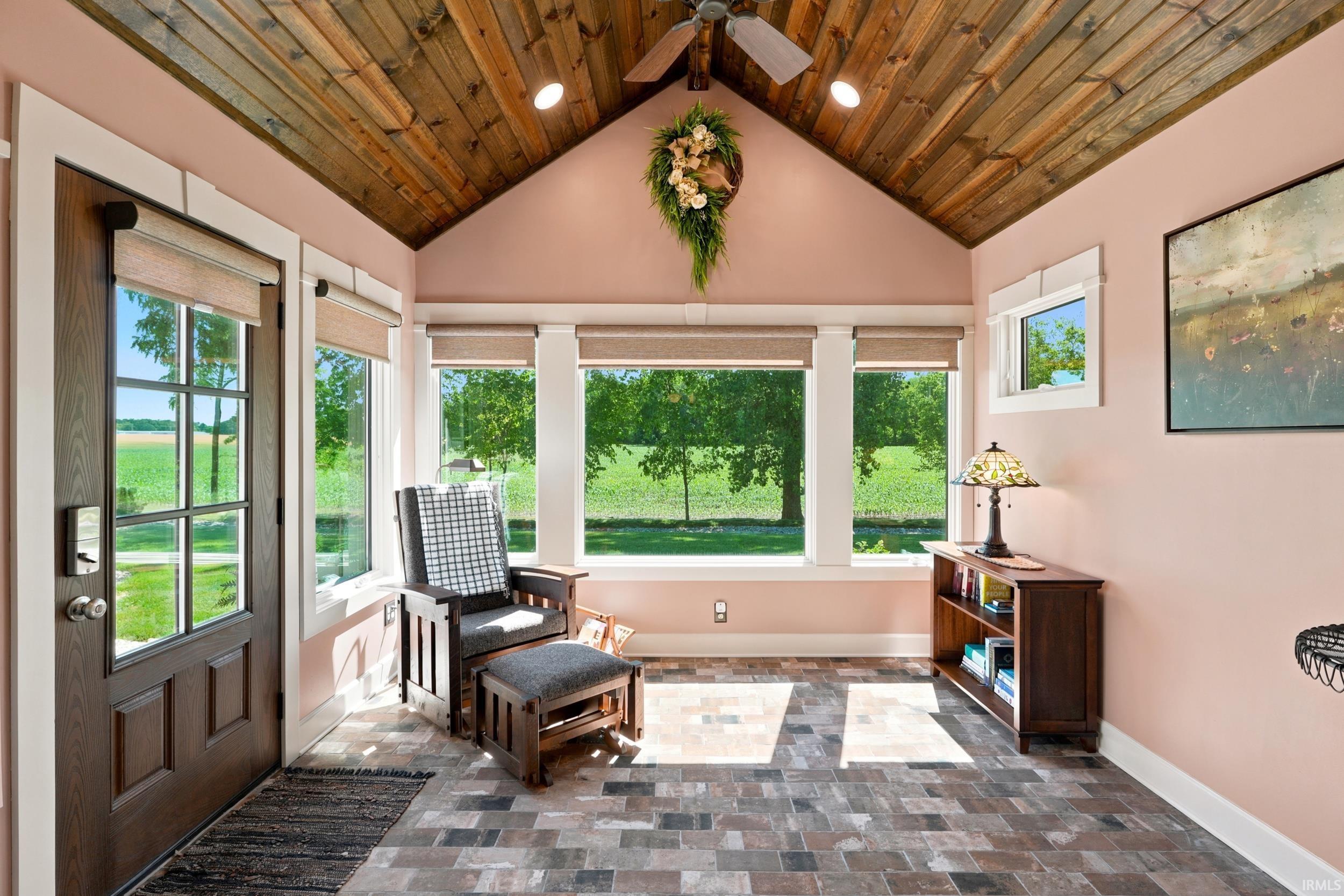 Vaulted wood-finish ceiling with exposed beams, paired with extensive window-line framing exterior greenery