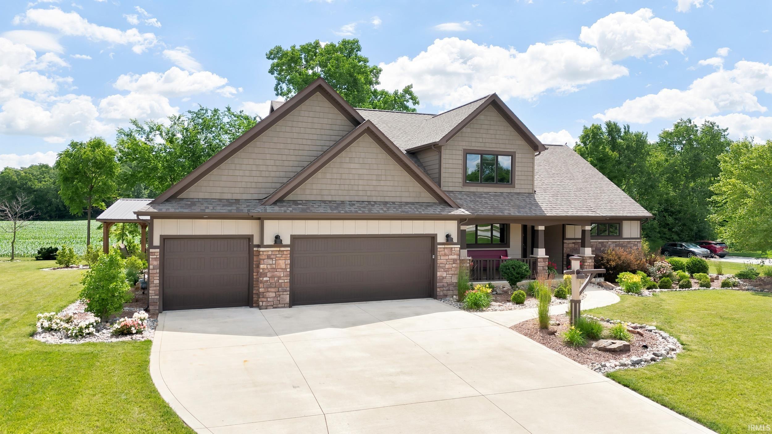 Two-story residence featuring a shingle and stone facade, a concrete driveway, and an attached two-car garage