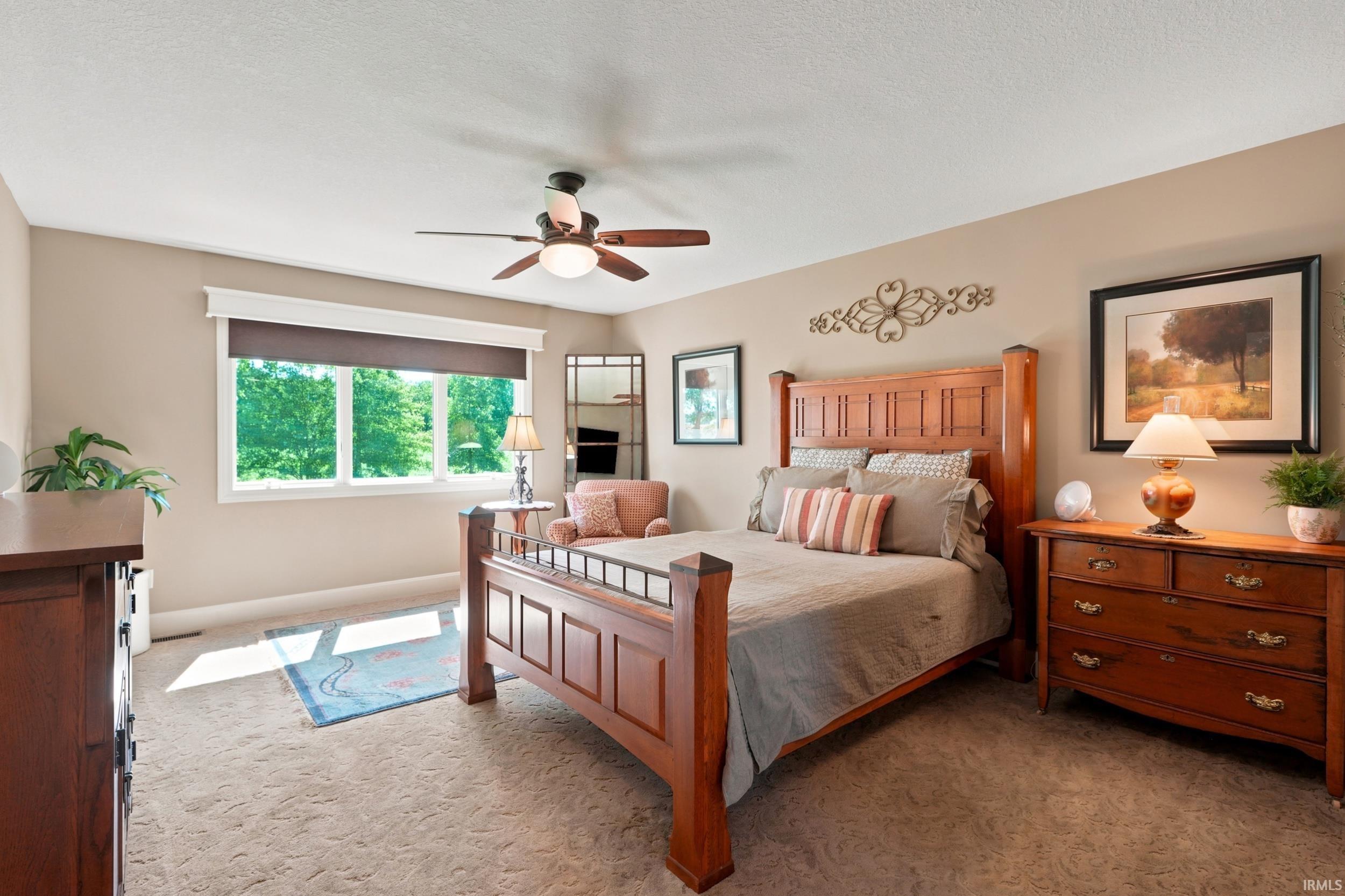 Spacious room featuring carpeting, a multi-pane window with trim and roller shade, and a ceiling fan with integrated lighting