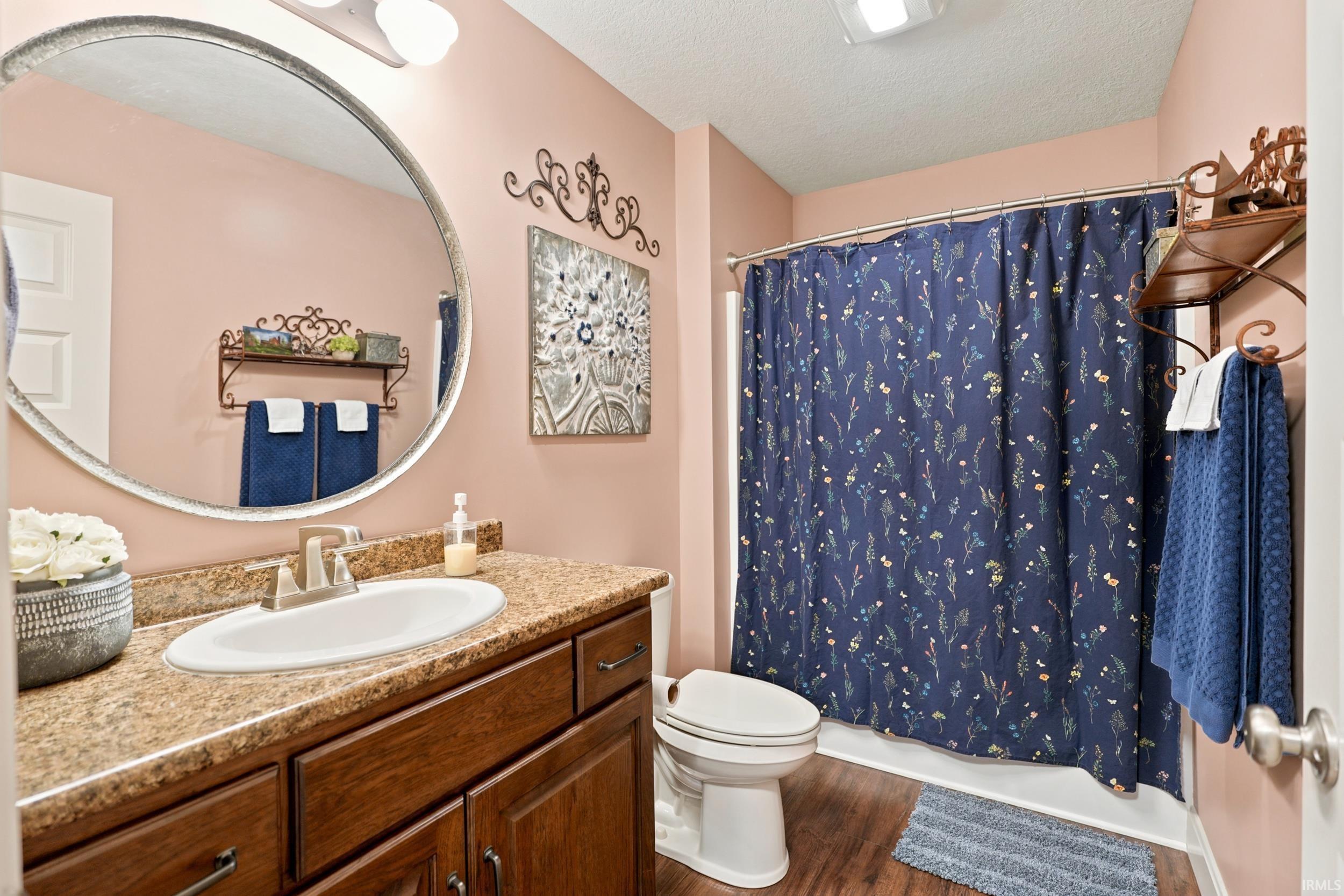 Bathroom featuring a wood-finish vanity with a light-colored countertop and an oval-shaped mirror