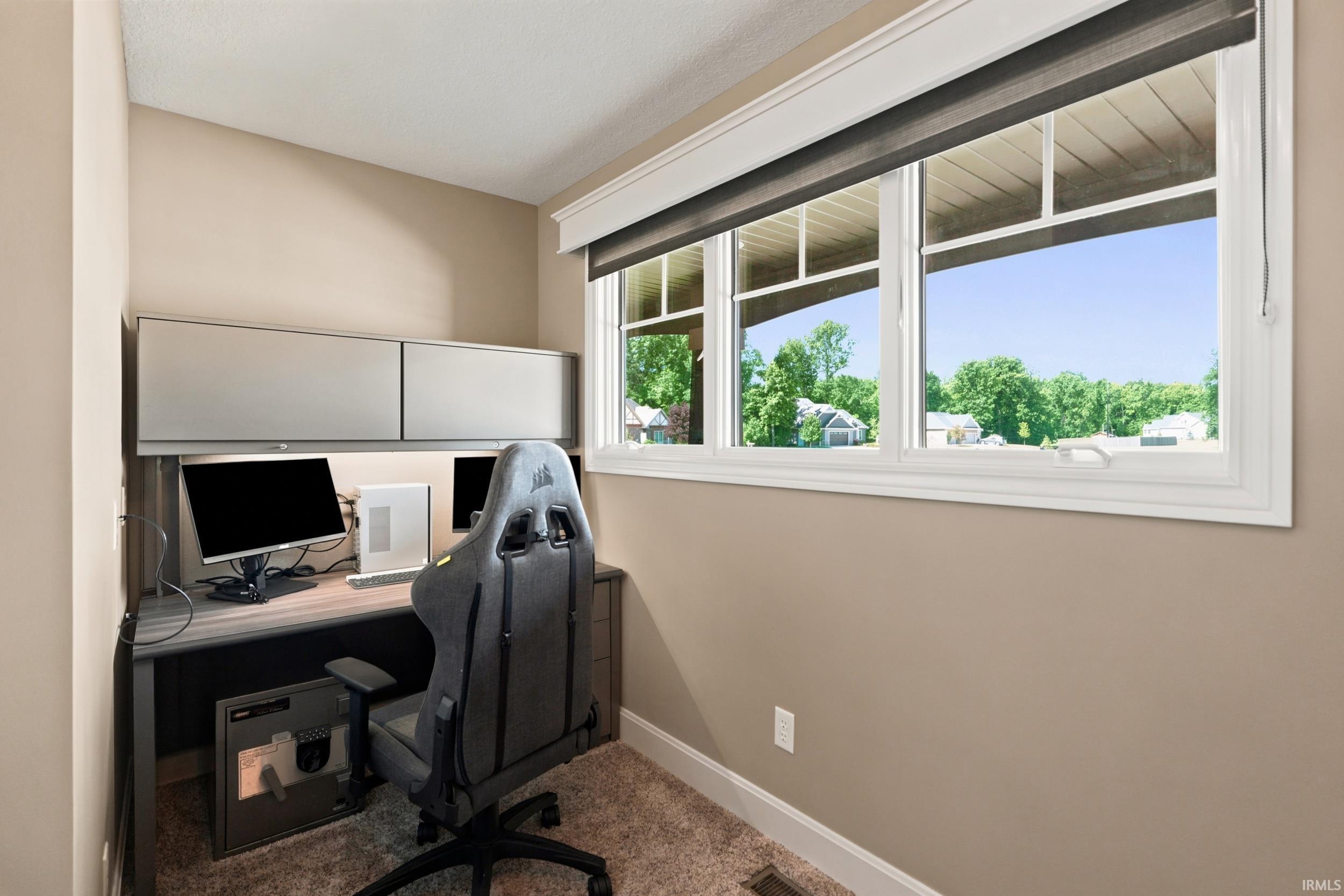 Built-in desk with upper cabinetry, neutral wall paint, white trim, and a window featuring an exterior landscape