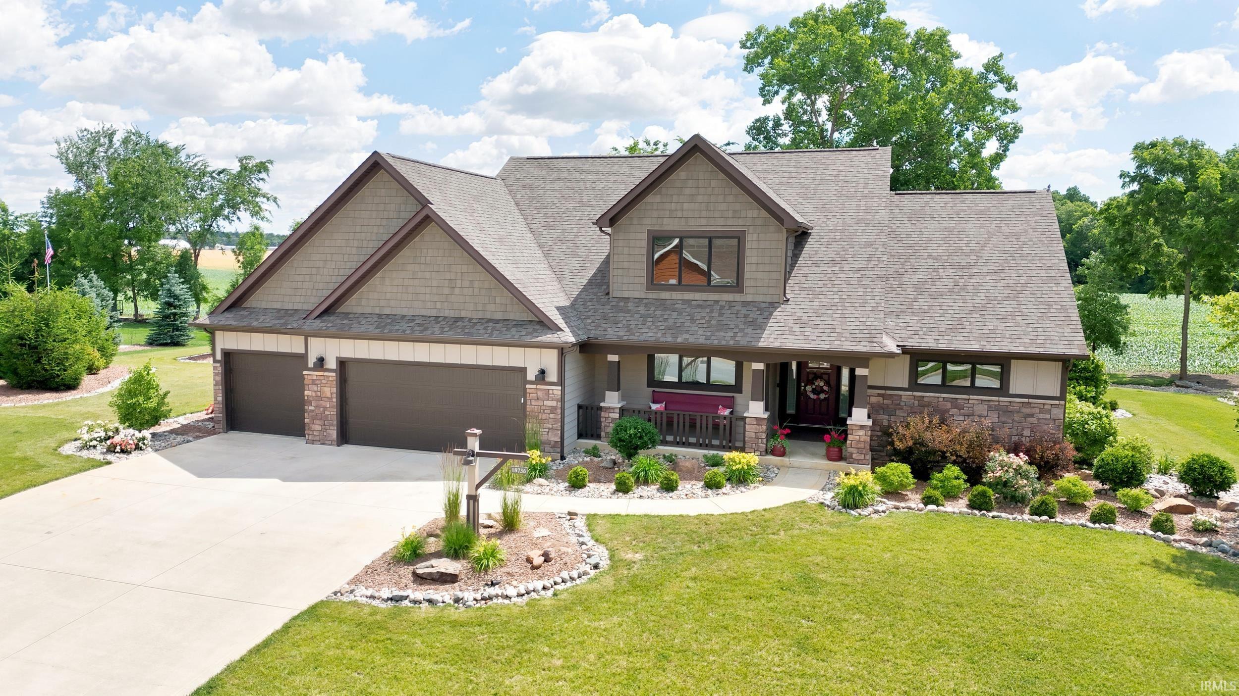 Craftsman-style residence featuring stone and shake siding accents, a three-car garage, concrete driveway, and established perimeter landscaping