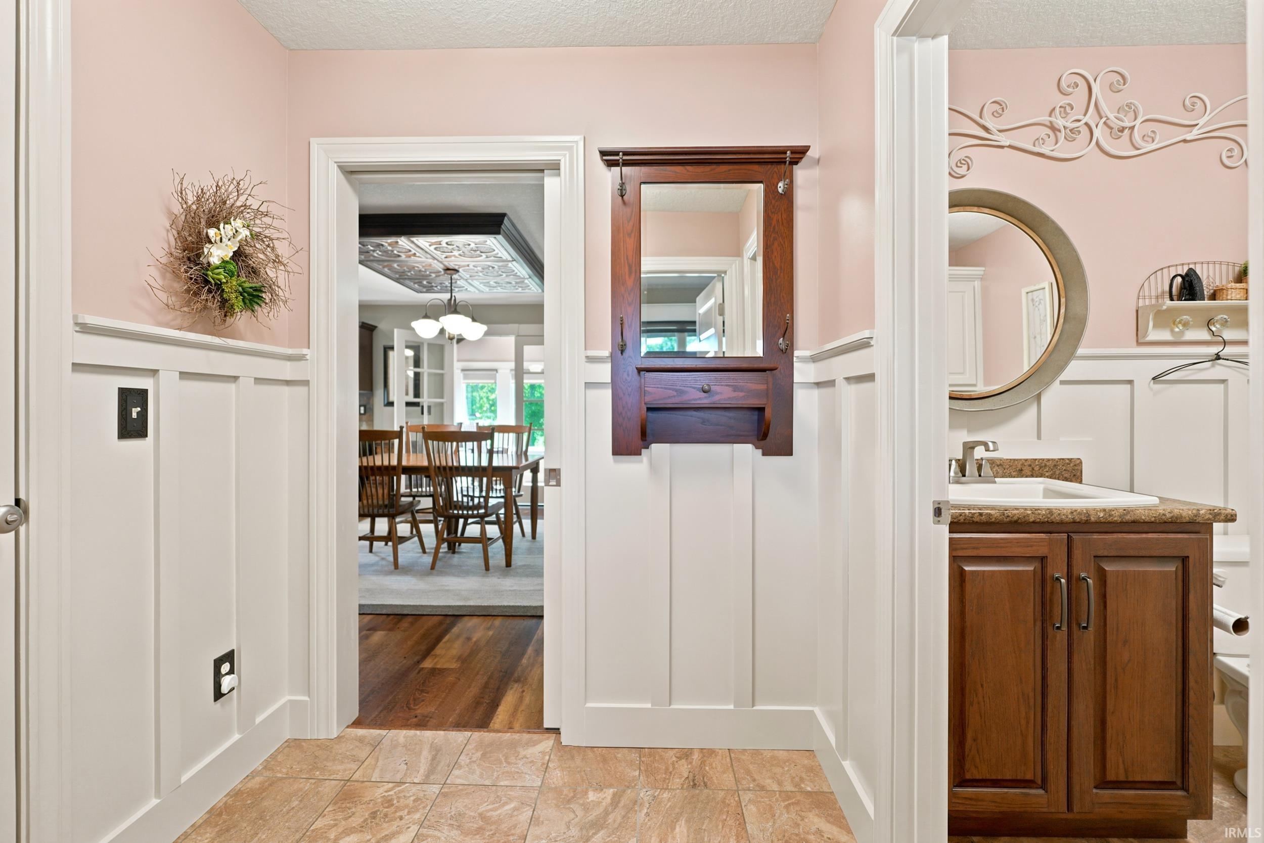 Hallway featuring tile flooring, white wainscoting, and a built-in wooden coat rack with mirror