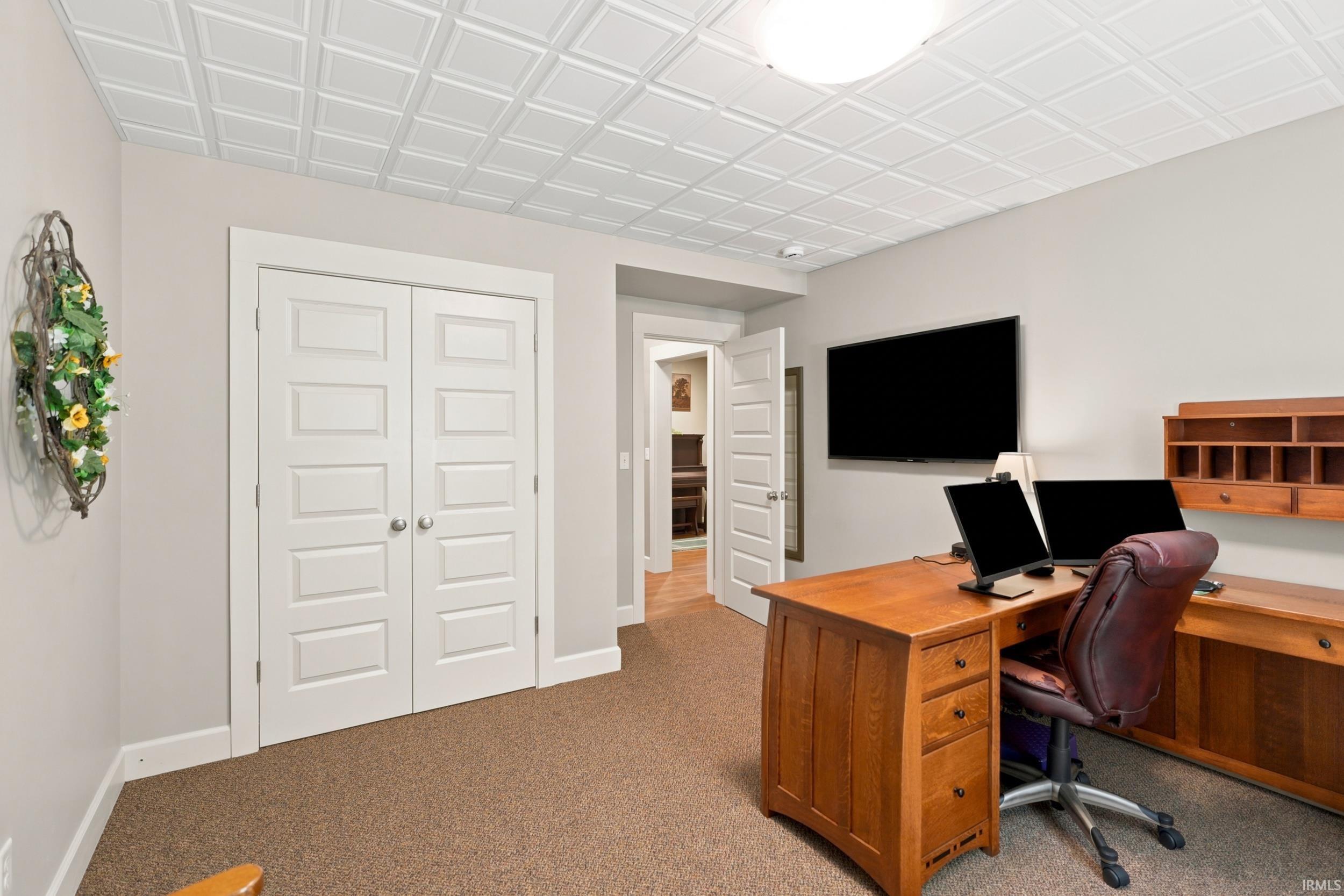 Versatile room featuring a decorative tile-patterned ceiling, light-toned walls, and plush carpeting