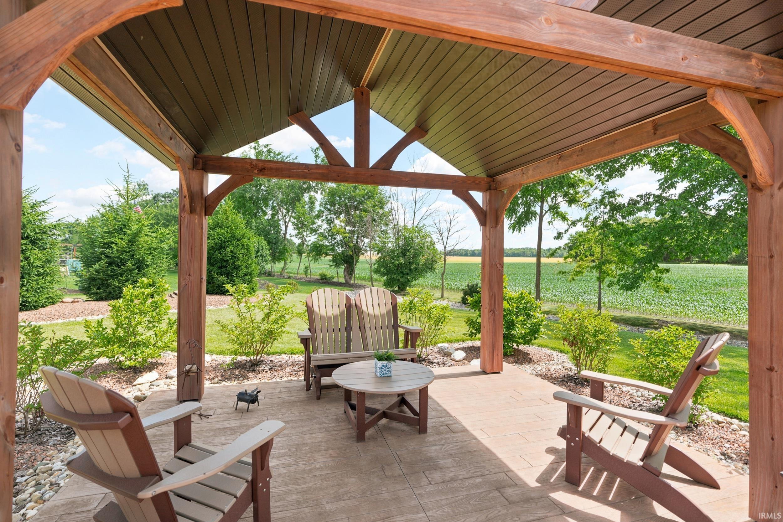 Expansive outdoor patio featuring a durable stamped concrete surface, a robust wood-beam pergola with a slatted ceiling, and mature perimeter landscaping