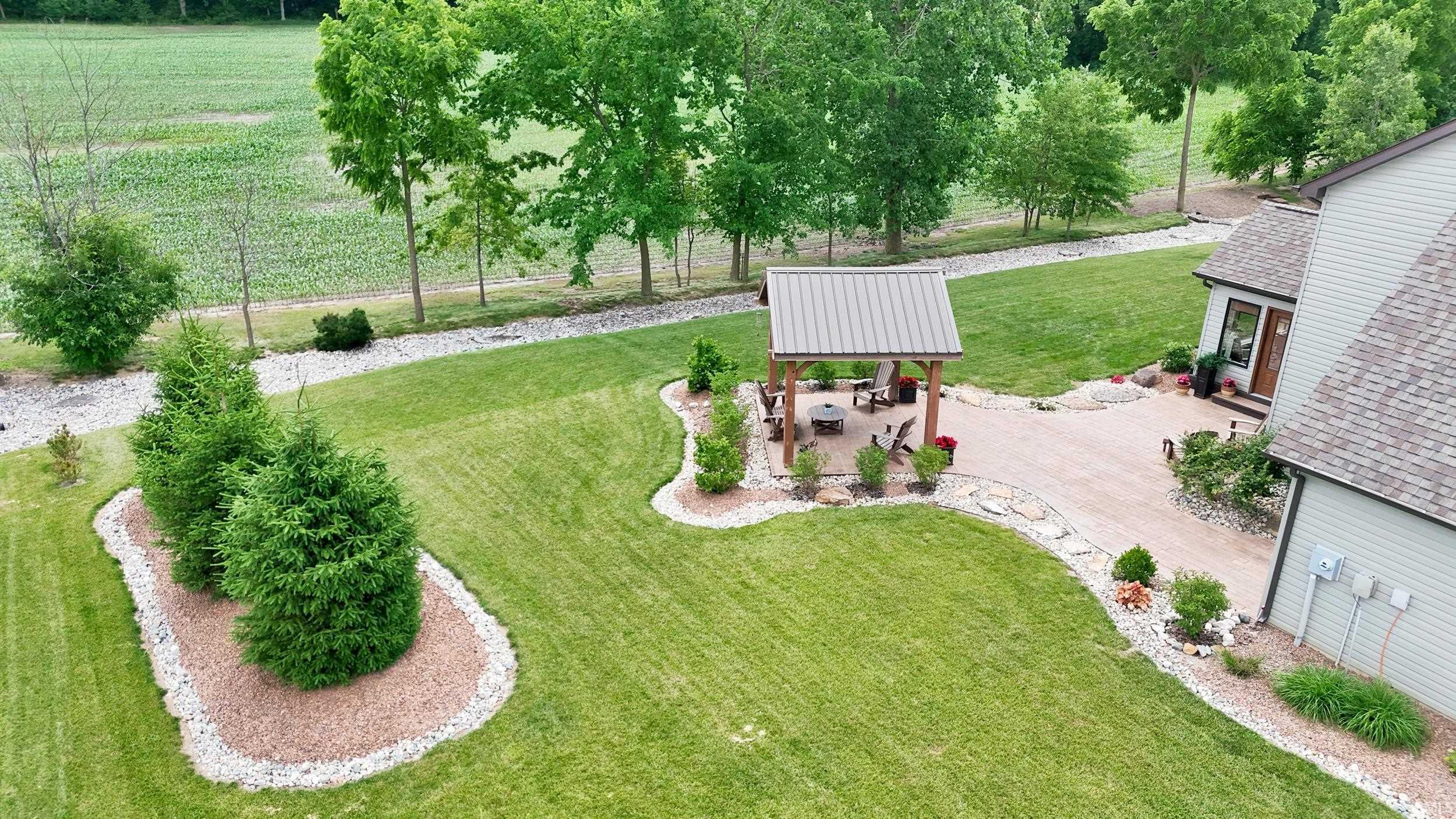 Expansive outdoor living area featuring a covered gazebo, paved patio, and established landscaping