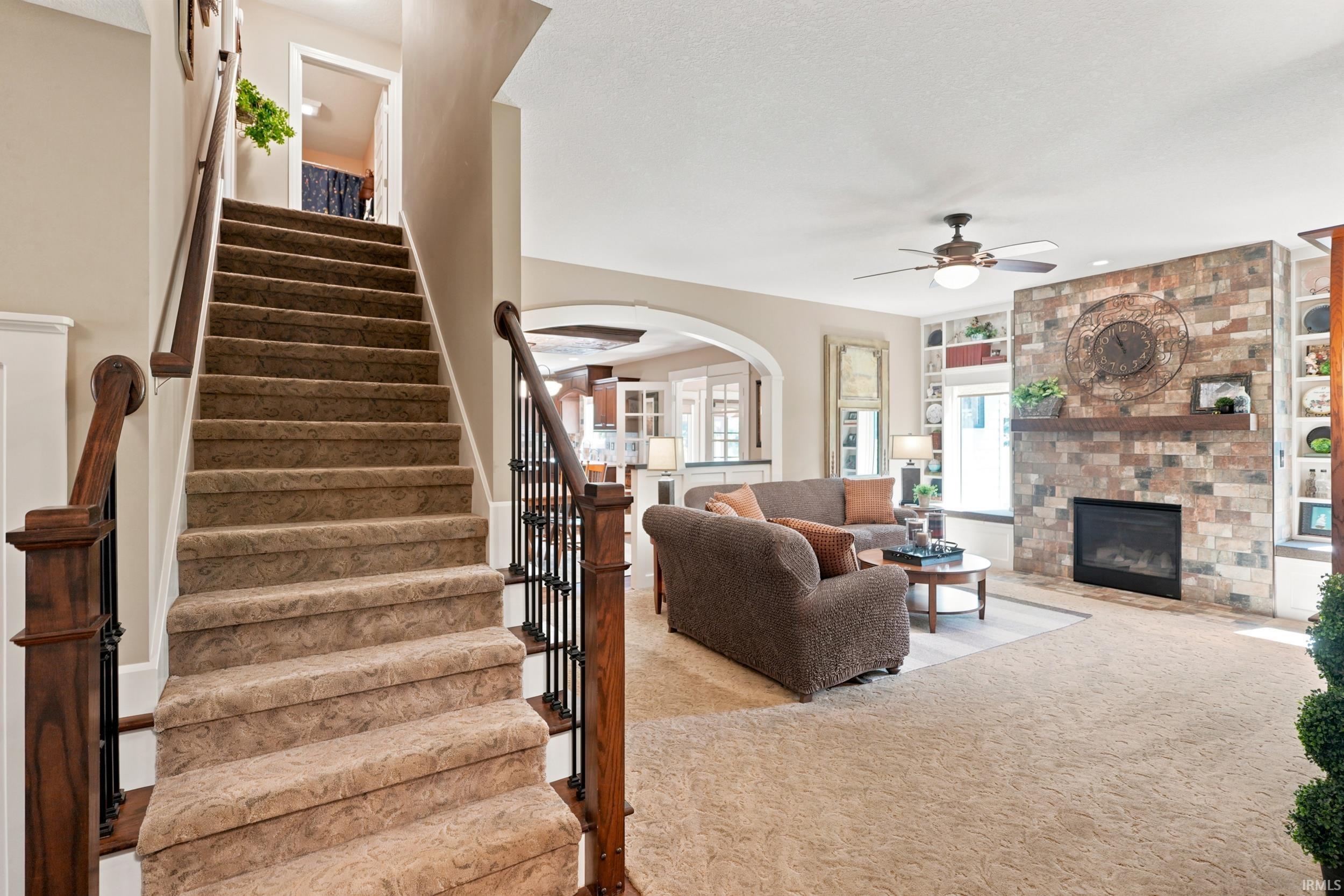 Staircase with carpeted treads and wood newel posts with iron balusters