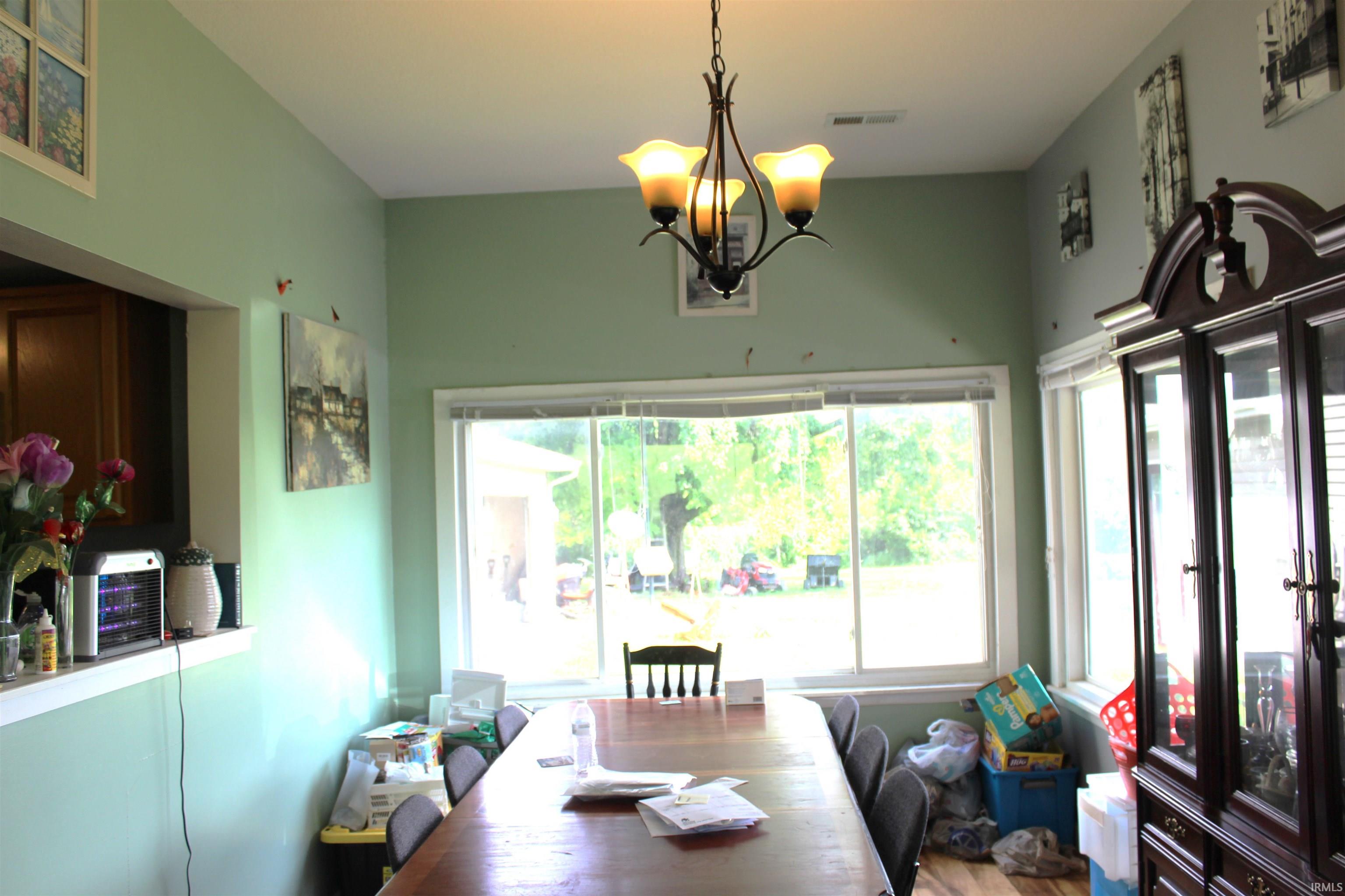 Dining area with a multi-light chandelier, a wide window with outdoor views, and a large built-in display cabinet