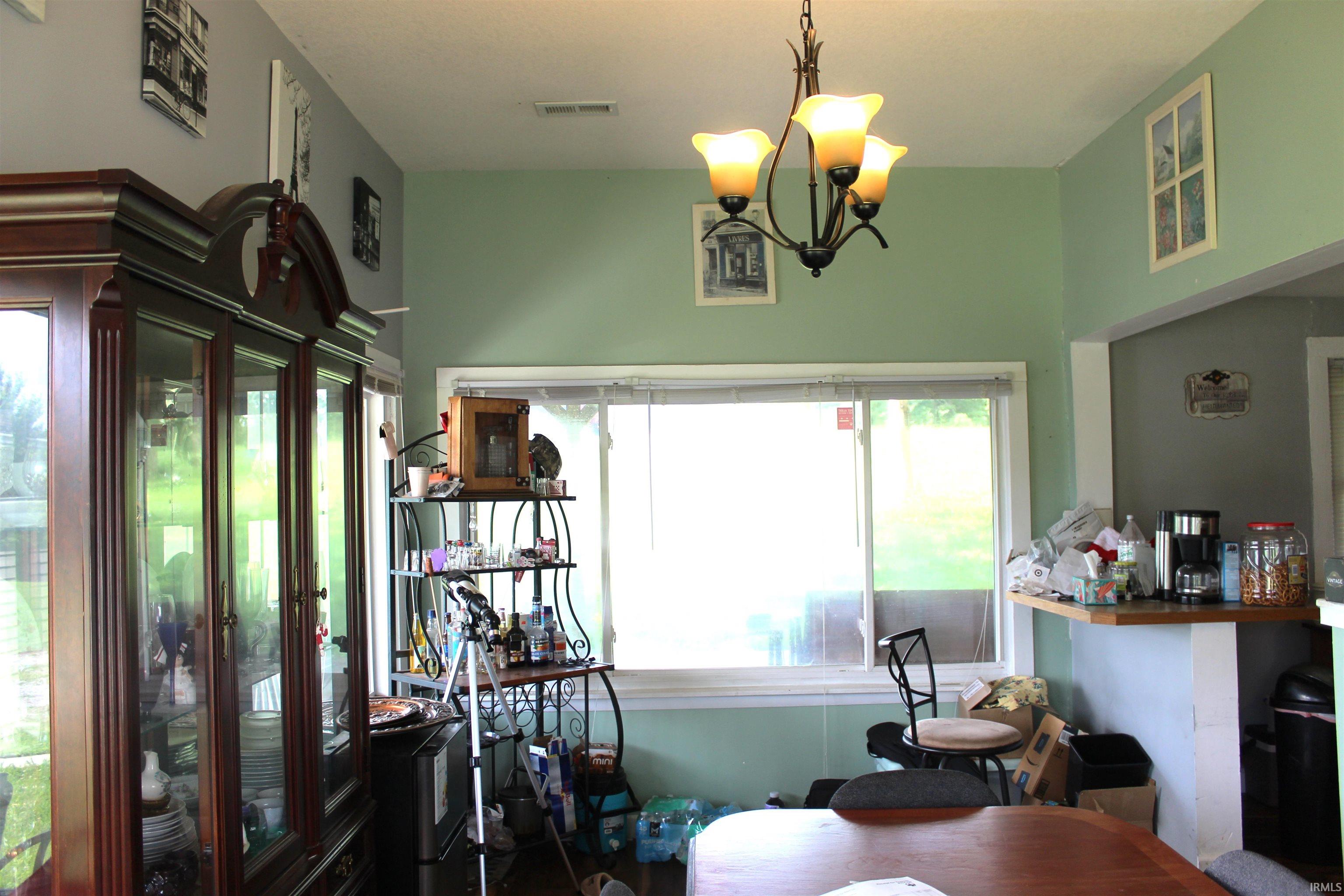 Bright interior space featuring a large sliding window, a light green wall color, a contemporary ceiling light fixture, and a built-in breakfast bar with a wood-finish countertop