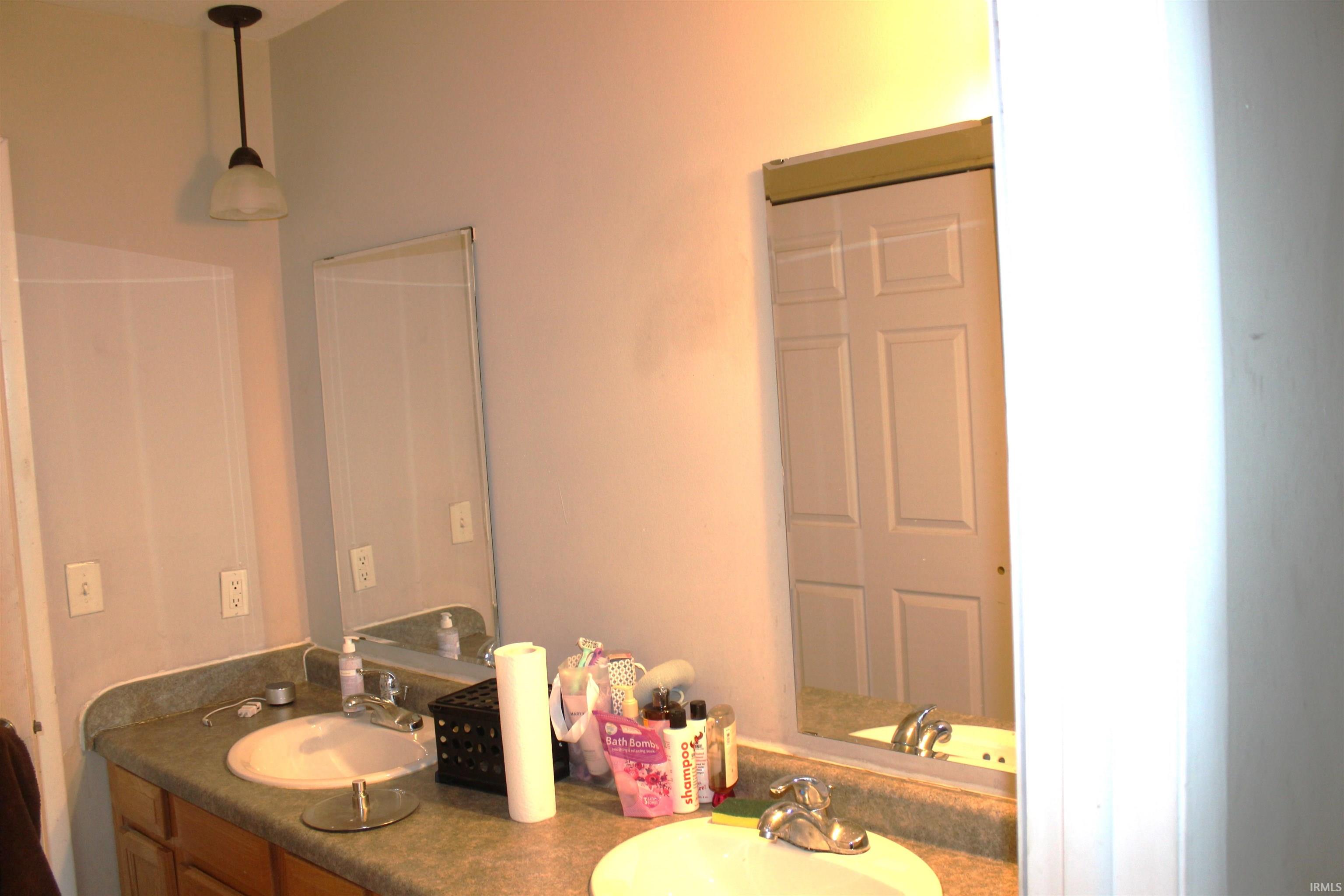 Bathroom featuring a dual vanity with integrated sinks, laminate countertops, and wall-mounted mirrors