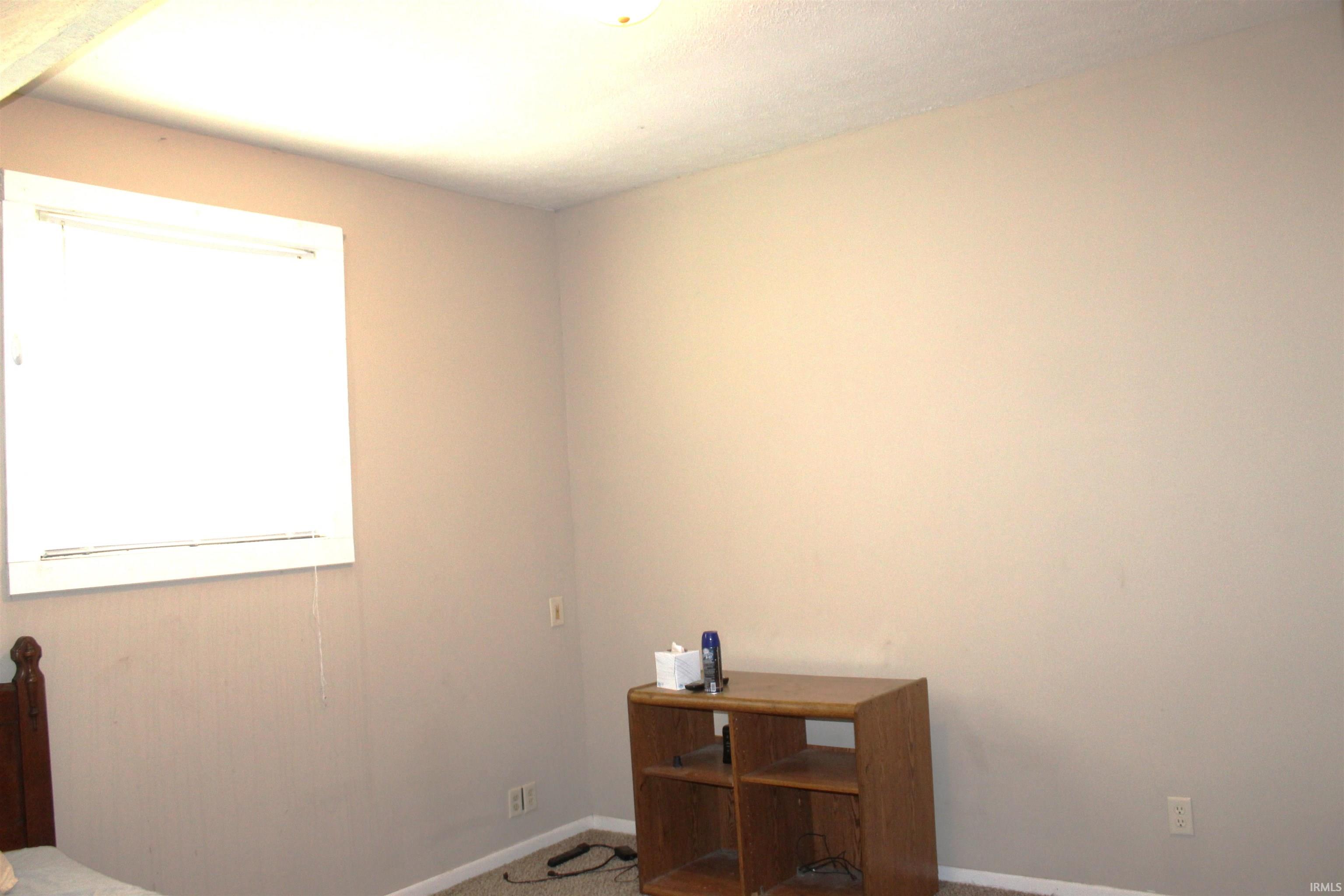 Interior room featuring neutral-toned walls, a white-framed window with blinds, and textured ceiling