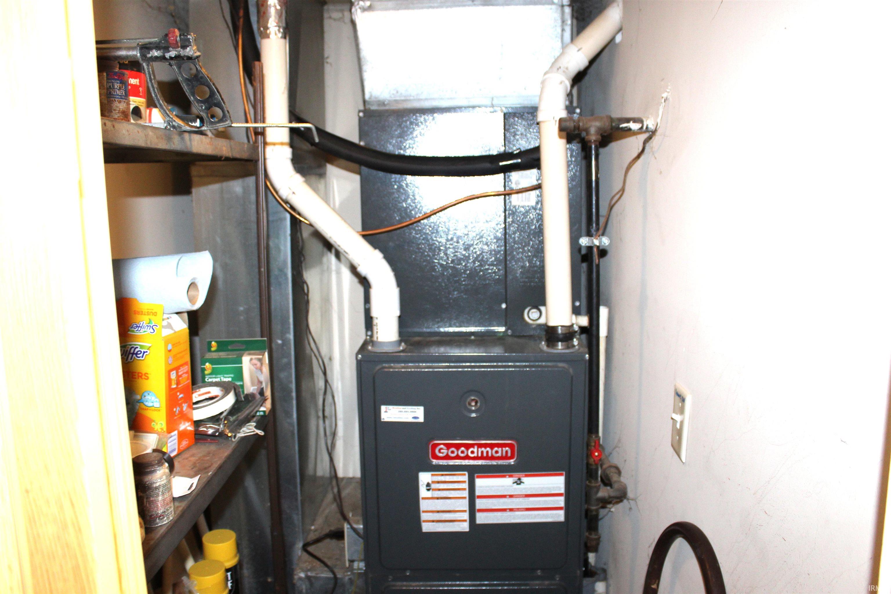 Dedicated utility space featuring a Goodman furnace unit with exposed ductwork and plumbing lines