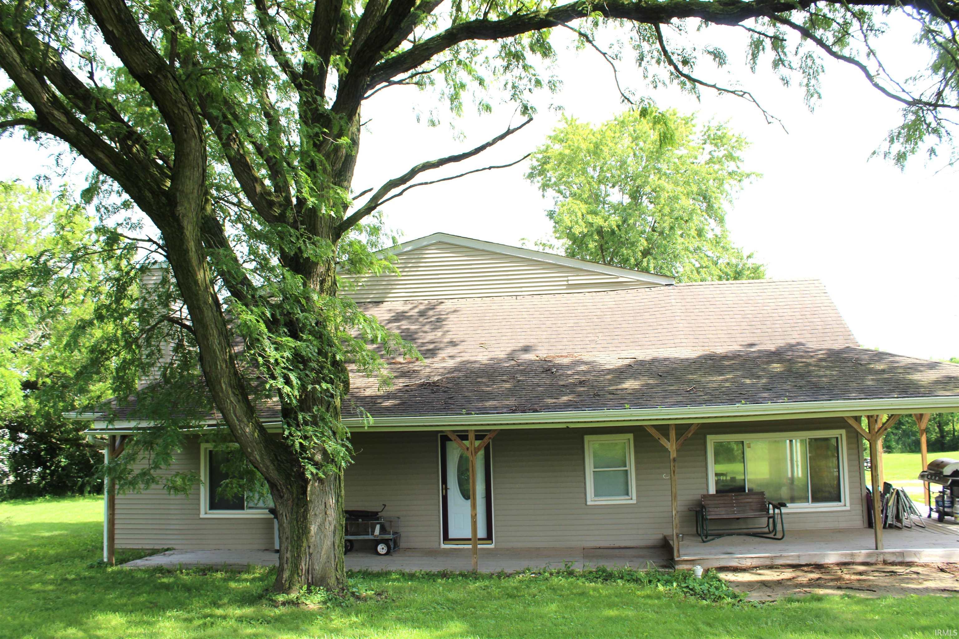 Single-family residence featuring a prominent mature tree, a covered front porch, and horizontal siding