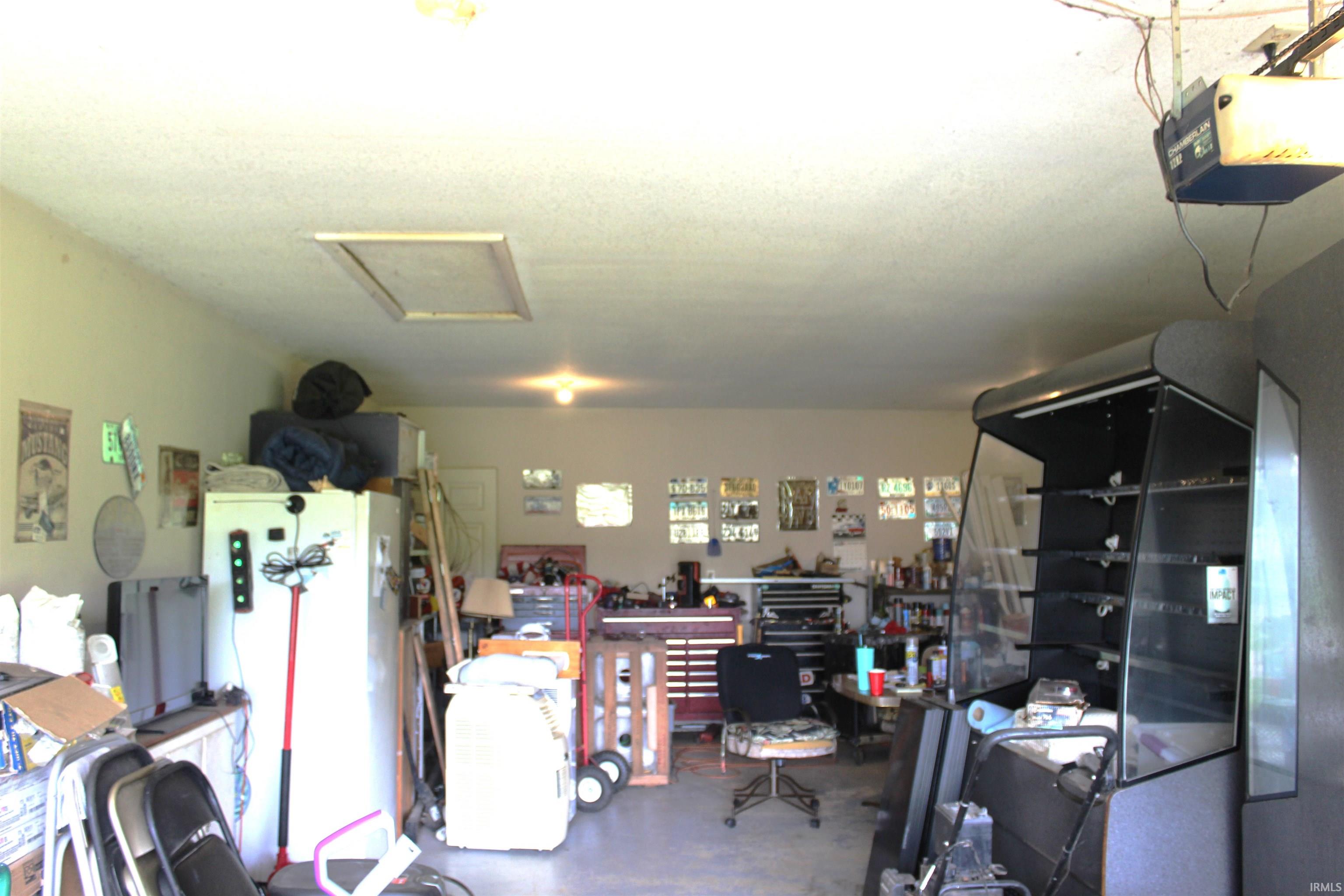 Spacious garage featuring a concrete floor, interior lighting, and a ceiling access panel