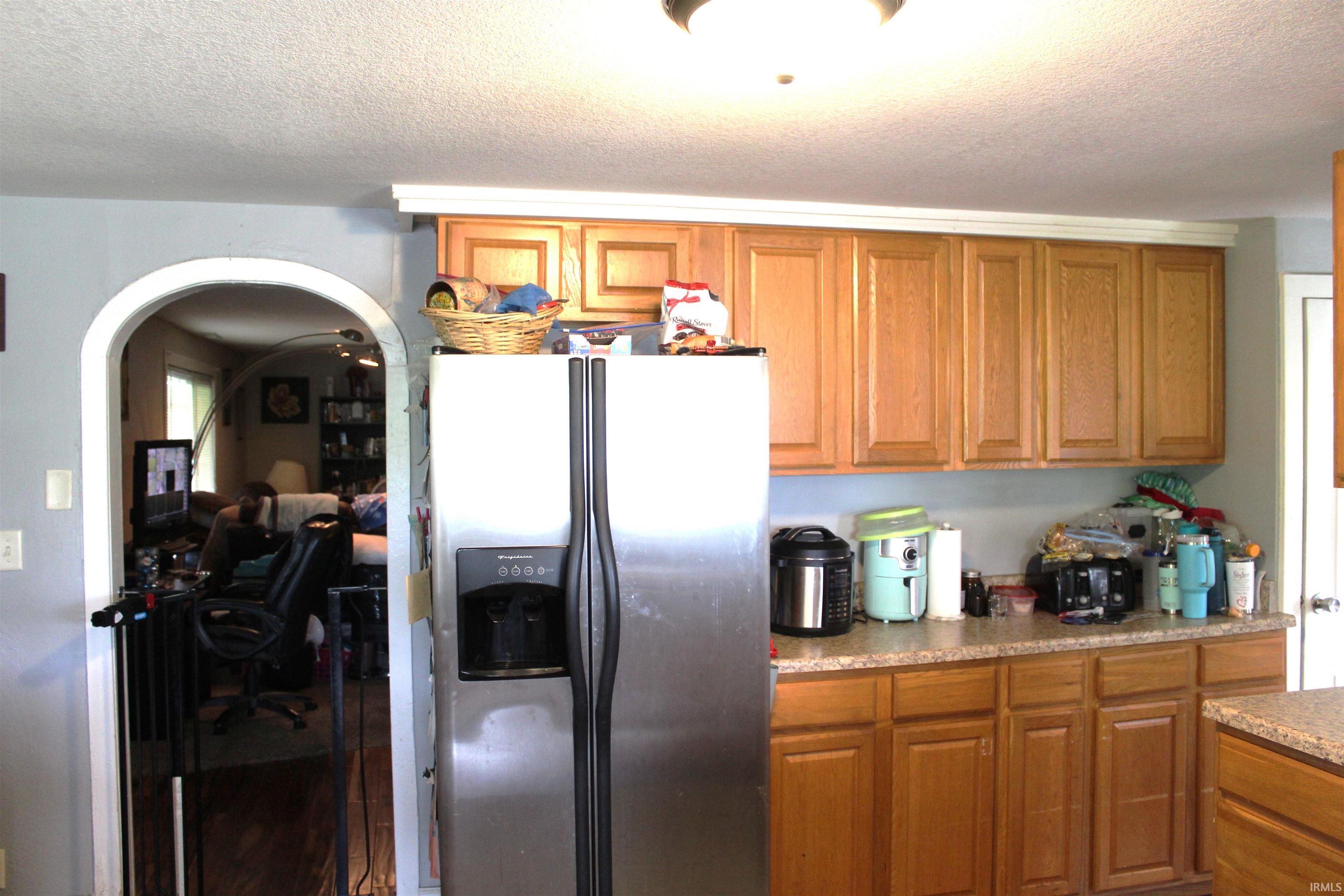 Kitchen featuring wood cabinetry, light-toned countertops, and a stainless steel refrigerator
