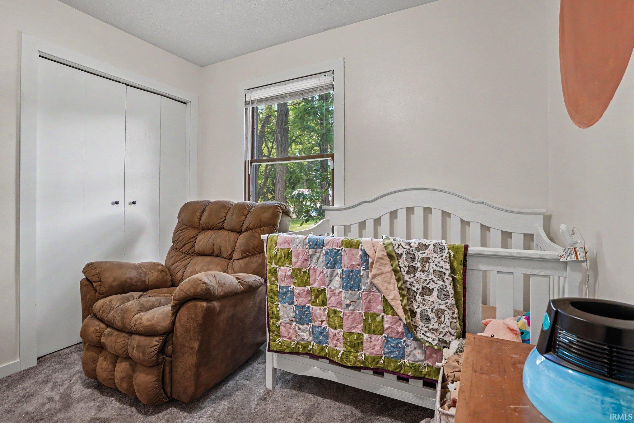 Carpeted room with a double-door closet featuring white bifold doors and dark hardware